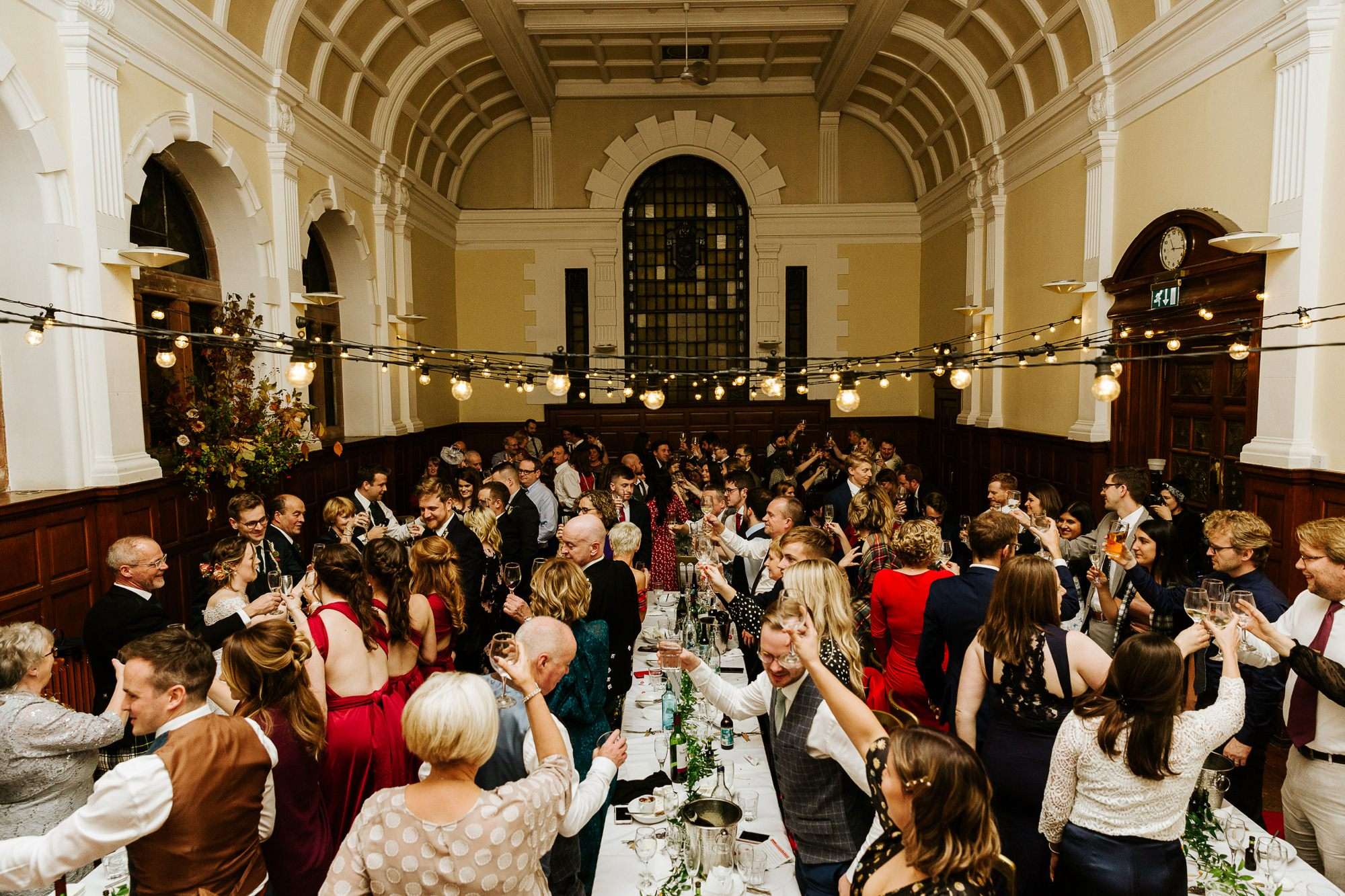 guests raising their glasses to toast a wedding in Pollokshields Burgh Hall in Glasgow 