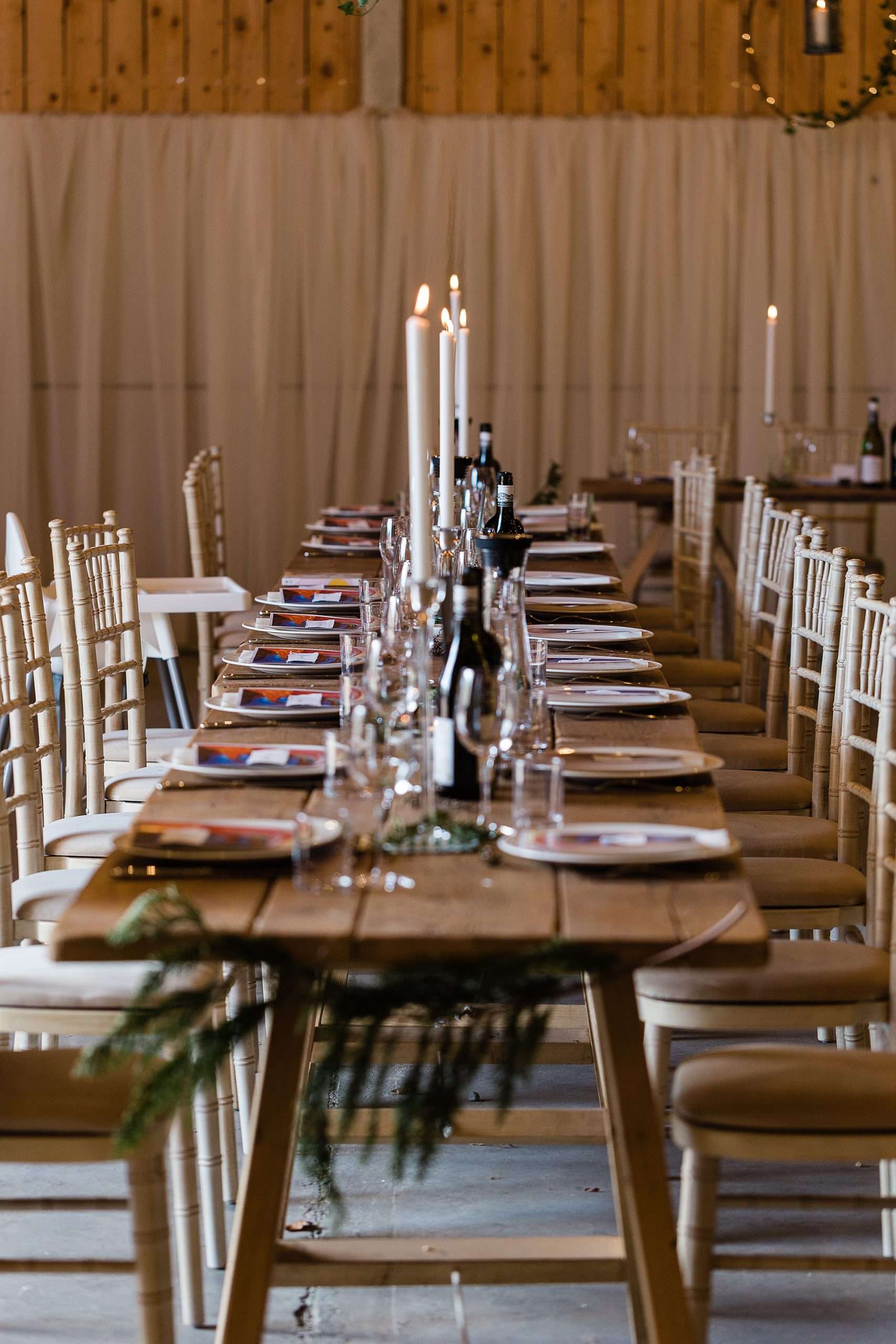 banquet style wedding table with candles in a barn