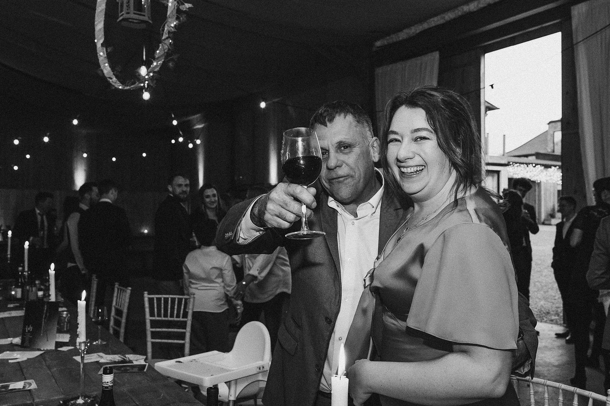 man holding up his glass of wine with a smiling woman next to him