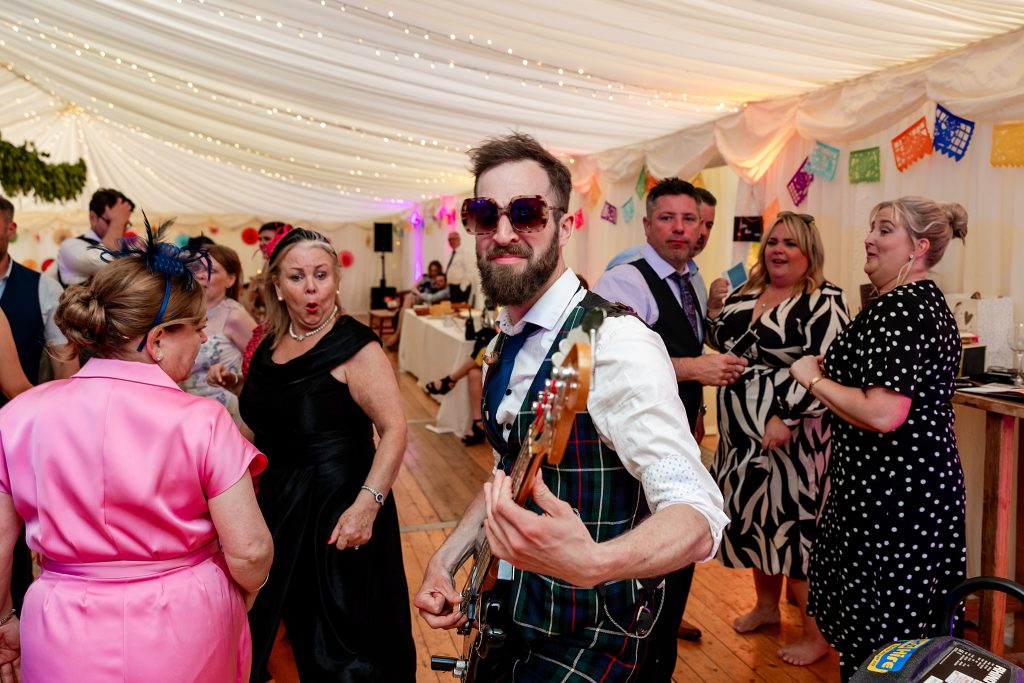 guitarist in sunglasses playing  in a marquee at a Scottish garden wedding