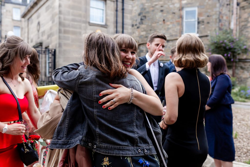 wedding guest in denim jacket hugging