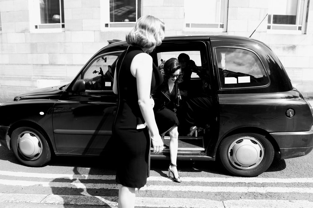 bridesmaids in black dresses climbing out of a black cab