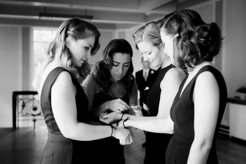 bridesmaids helping each other with friendship bracelets