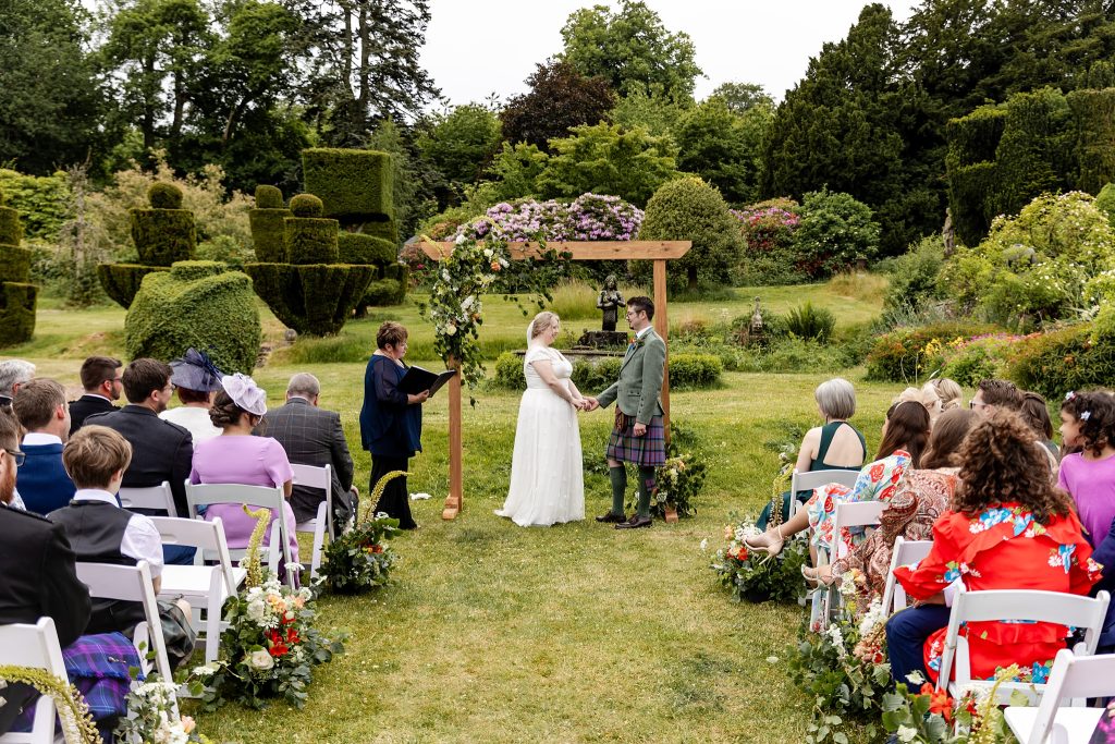 couple exchanging rings at outdoor wedding ceremony at Fingask Castle