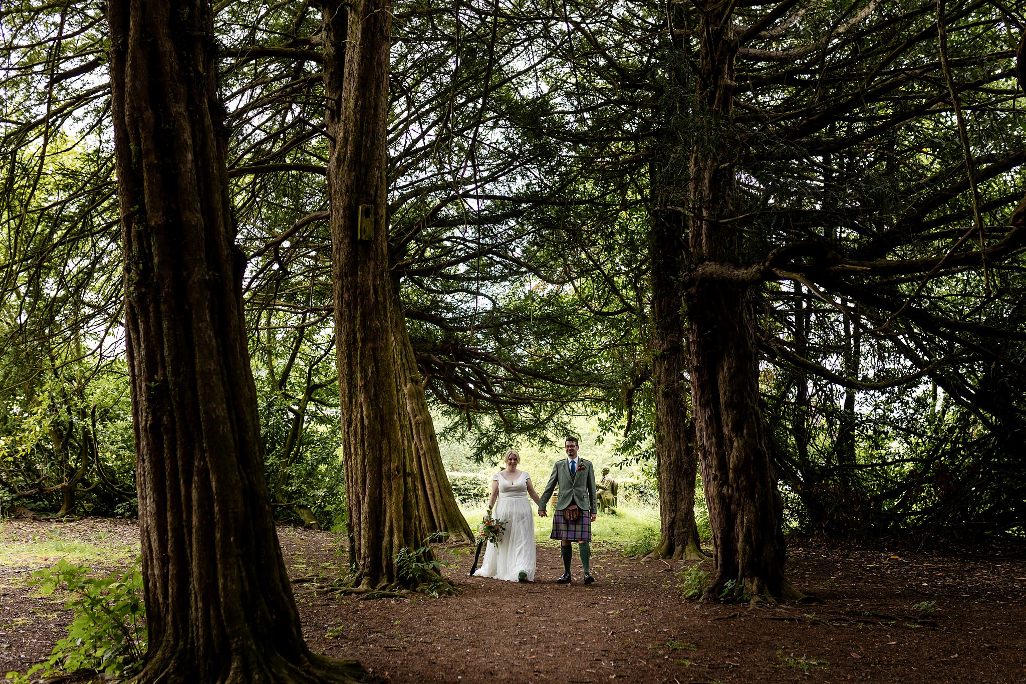 bride and groom exploring woodland at wedding at Fingask Castle