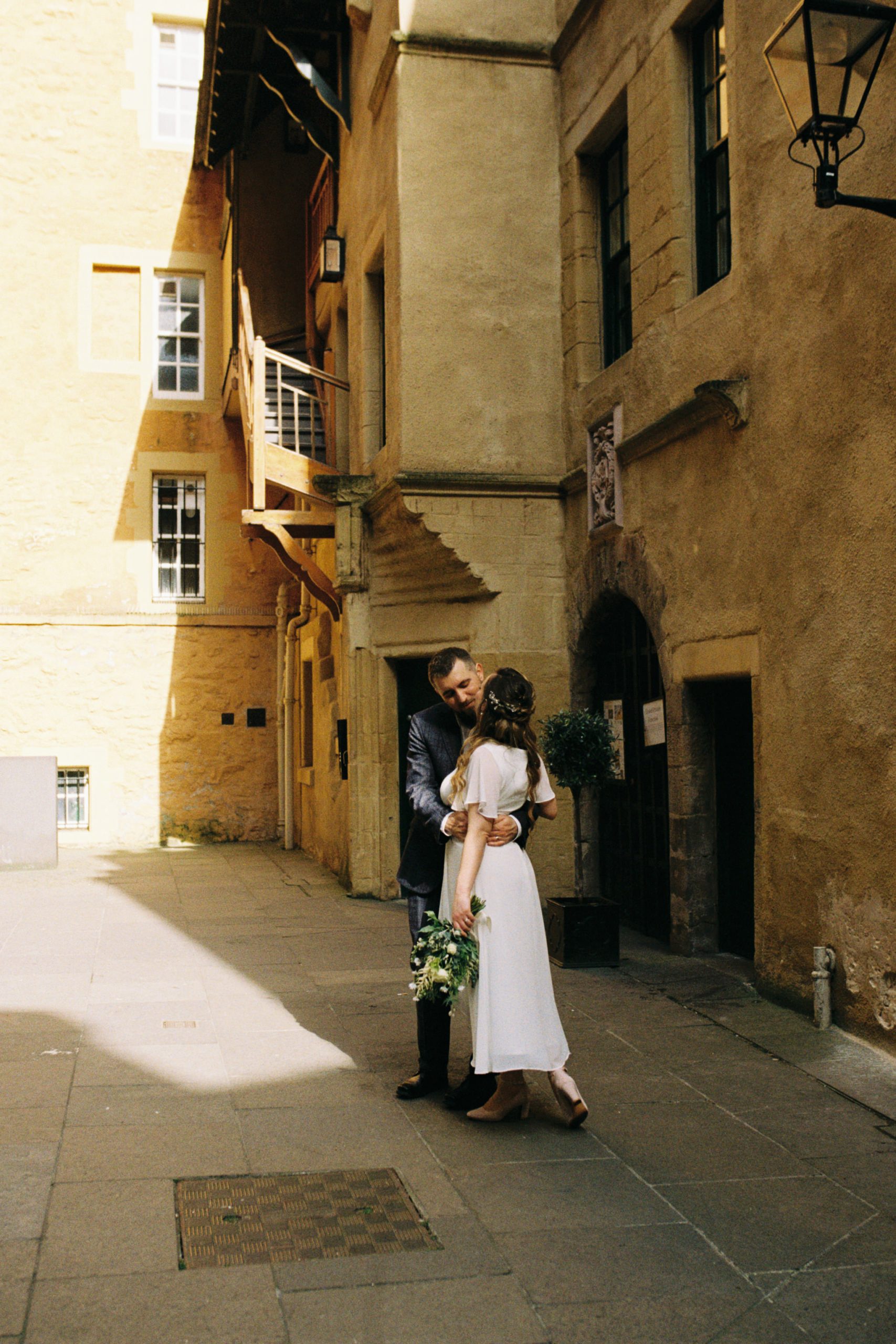analogue film photograph of bride and groom embracing in Riddles Court, off Royal Mile in Edinburgh