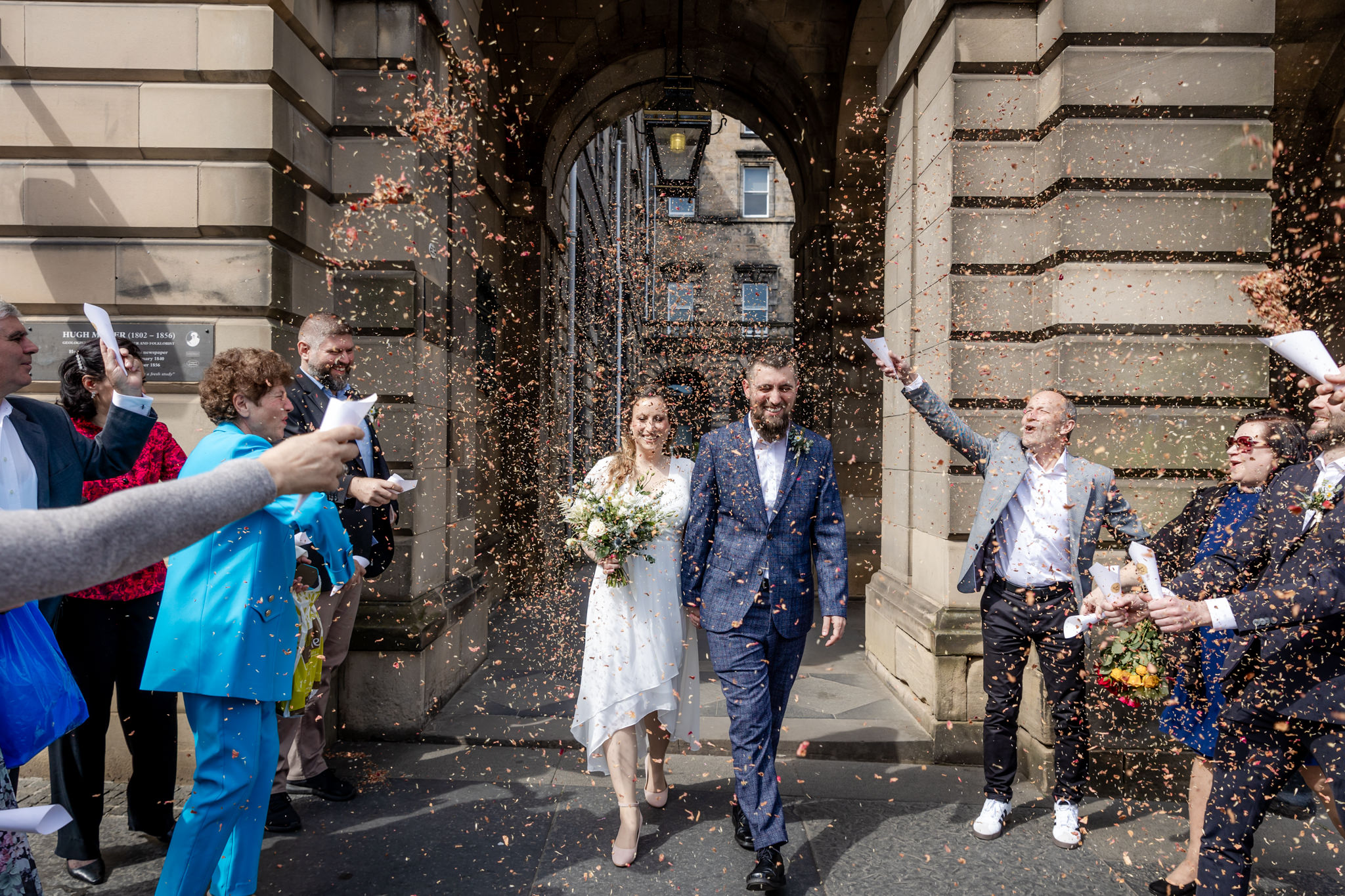 bride and groom walking through confetti on Royal Mile next to at City Chambers in Edinburgh