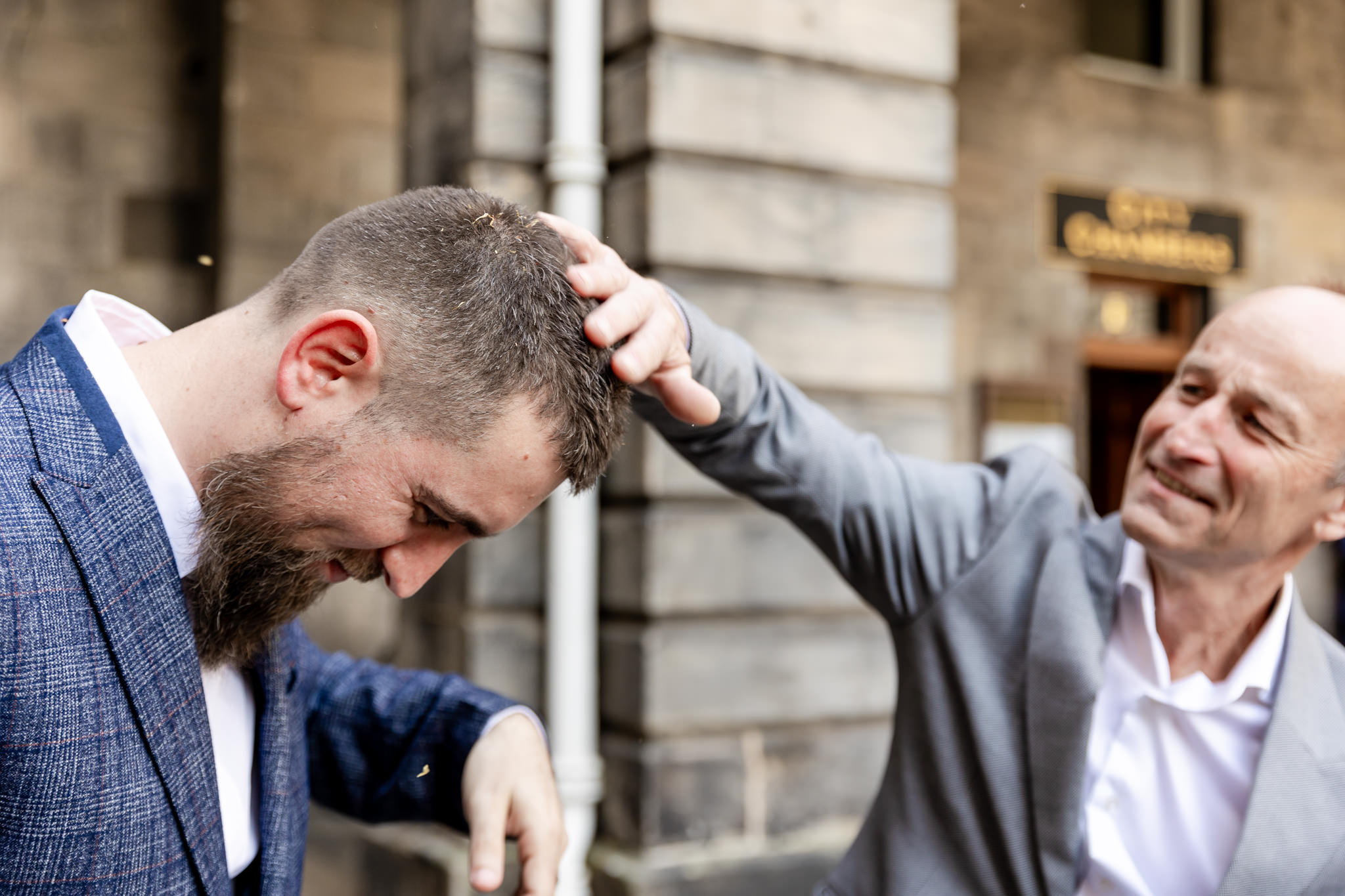 man brushing confetti out of groom's hair