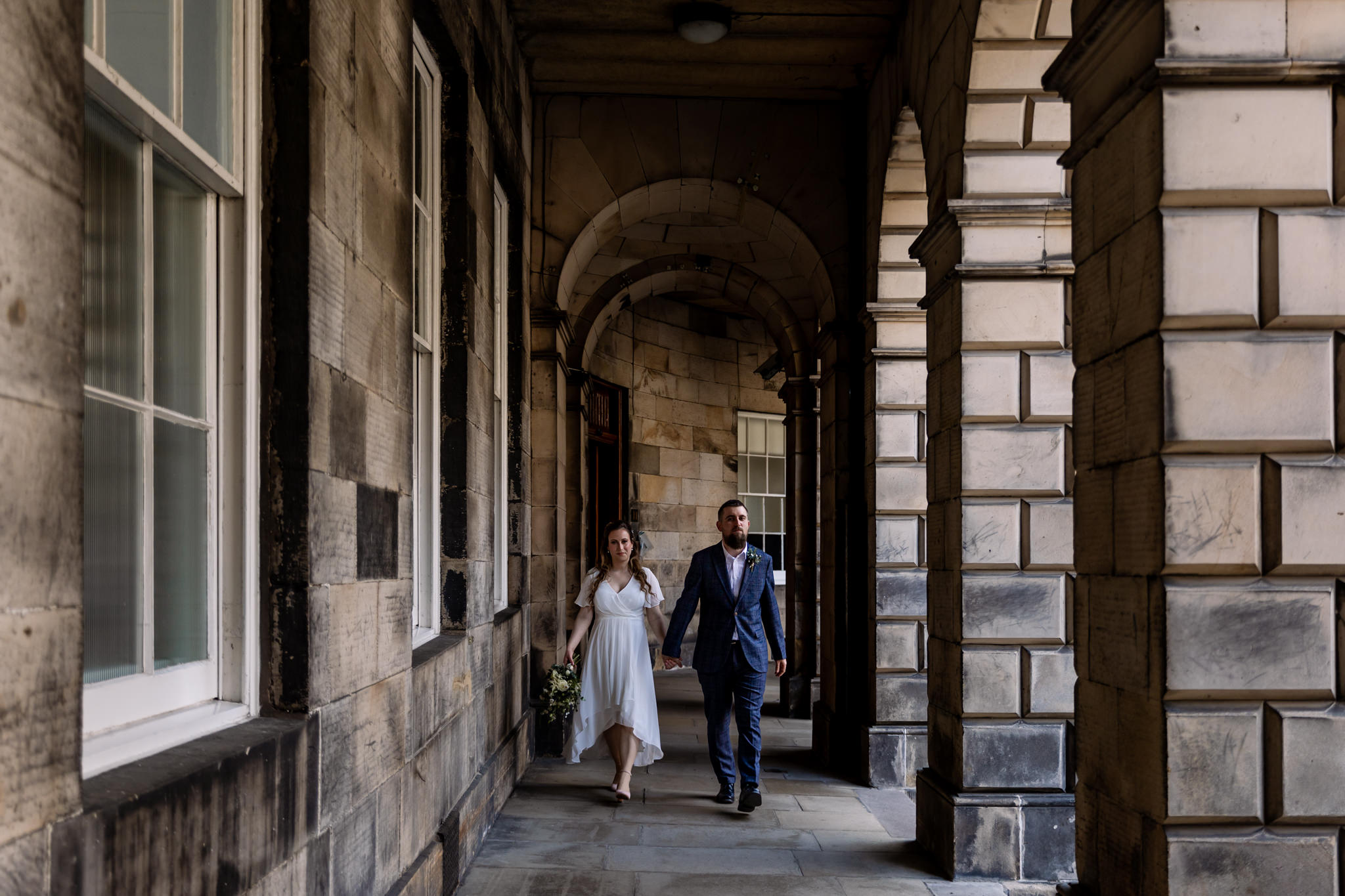 bride and groom walking through archways at Parliament Square, off Royal Mile in Edinburgh 
