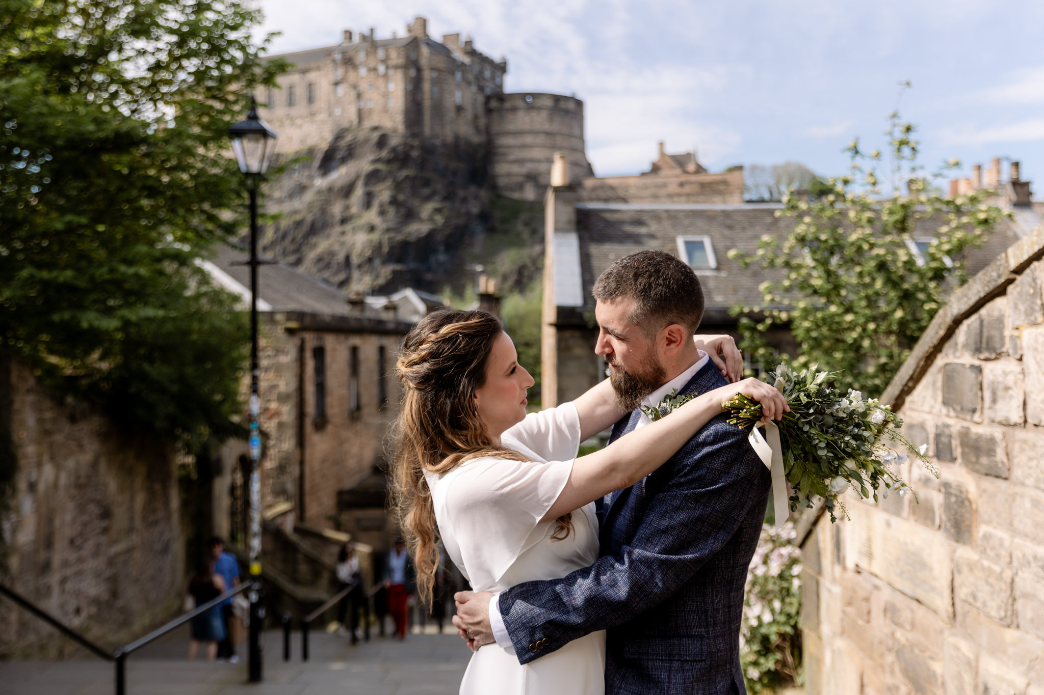 bride and groom embracing on the Vennel in Edinburgh with Edinburgh Castle in the background