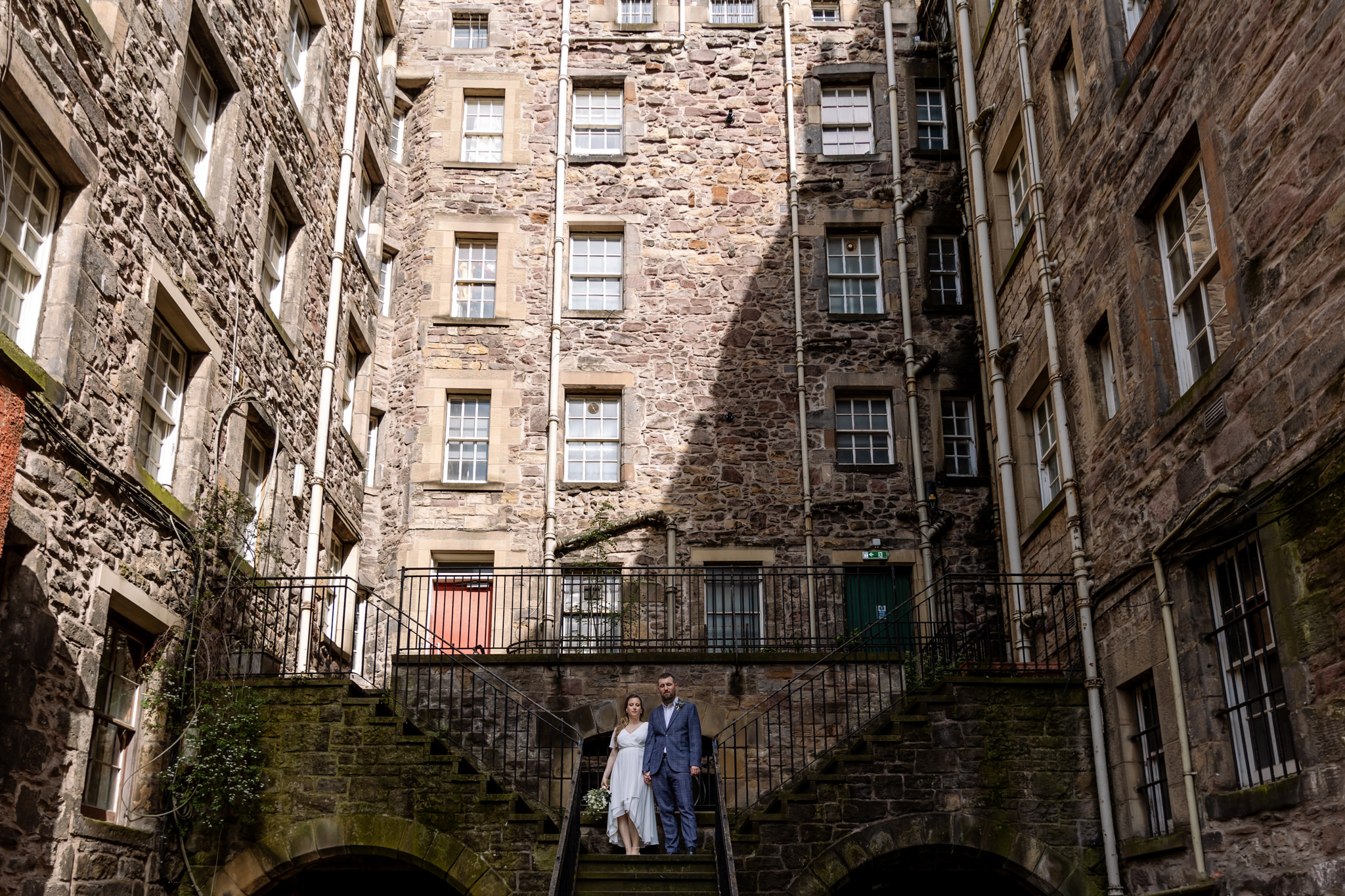bride and groom standing on staircase in Edinburgh old town