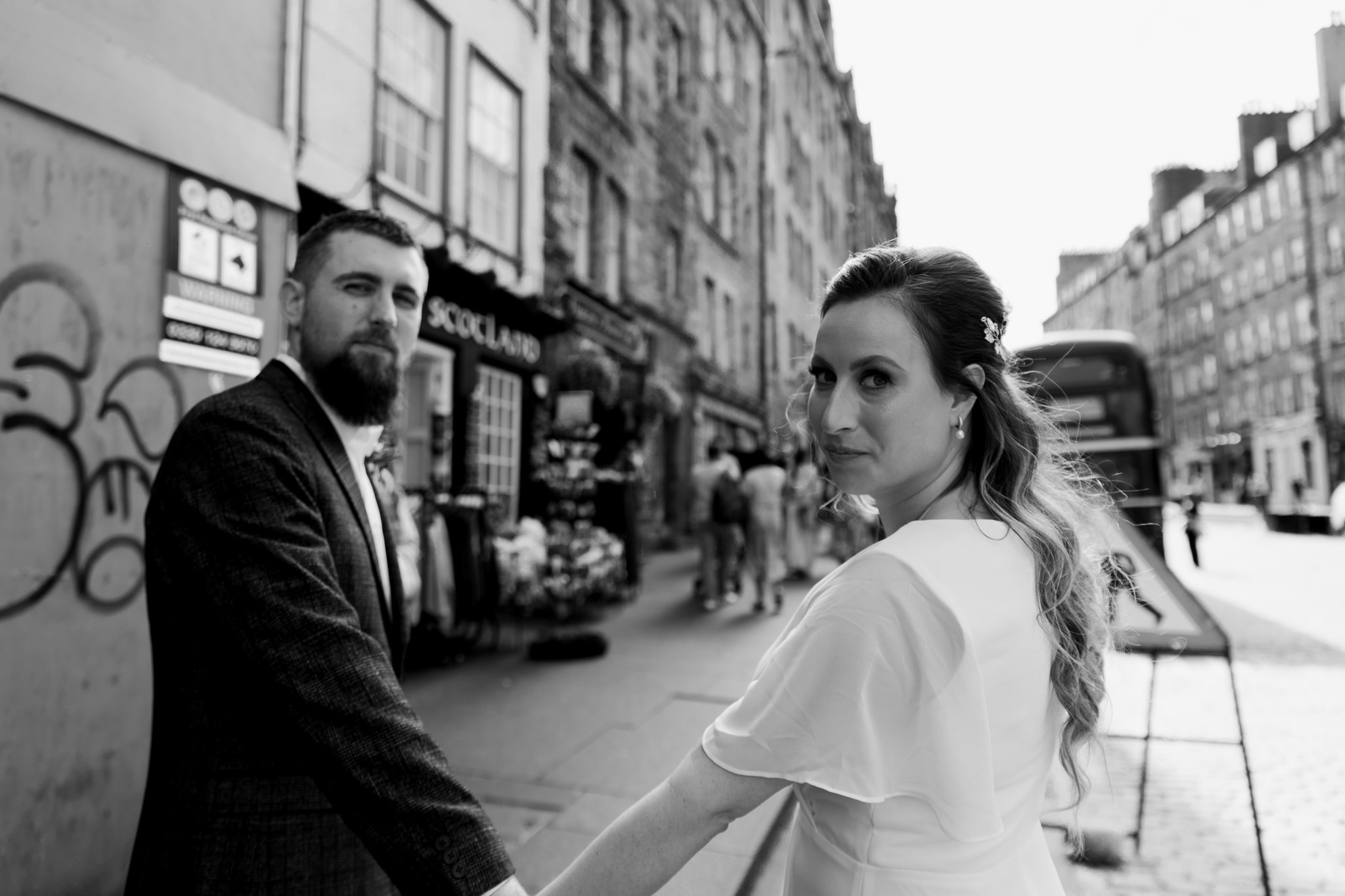 bride and groom walking through Old Town in Edinburgh looking over their shoulder