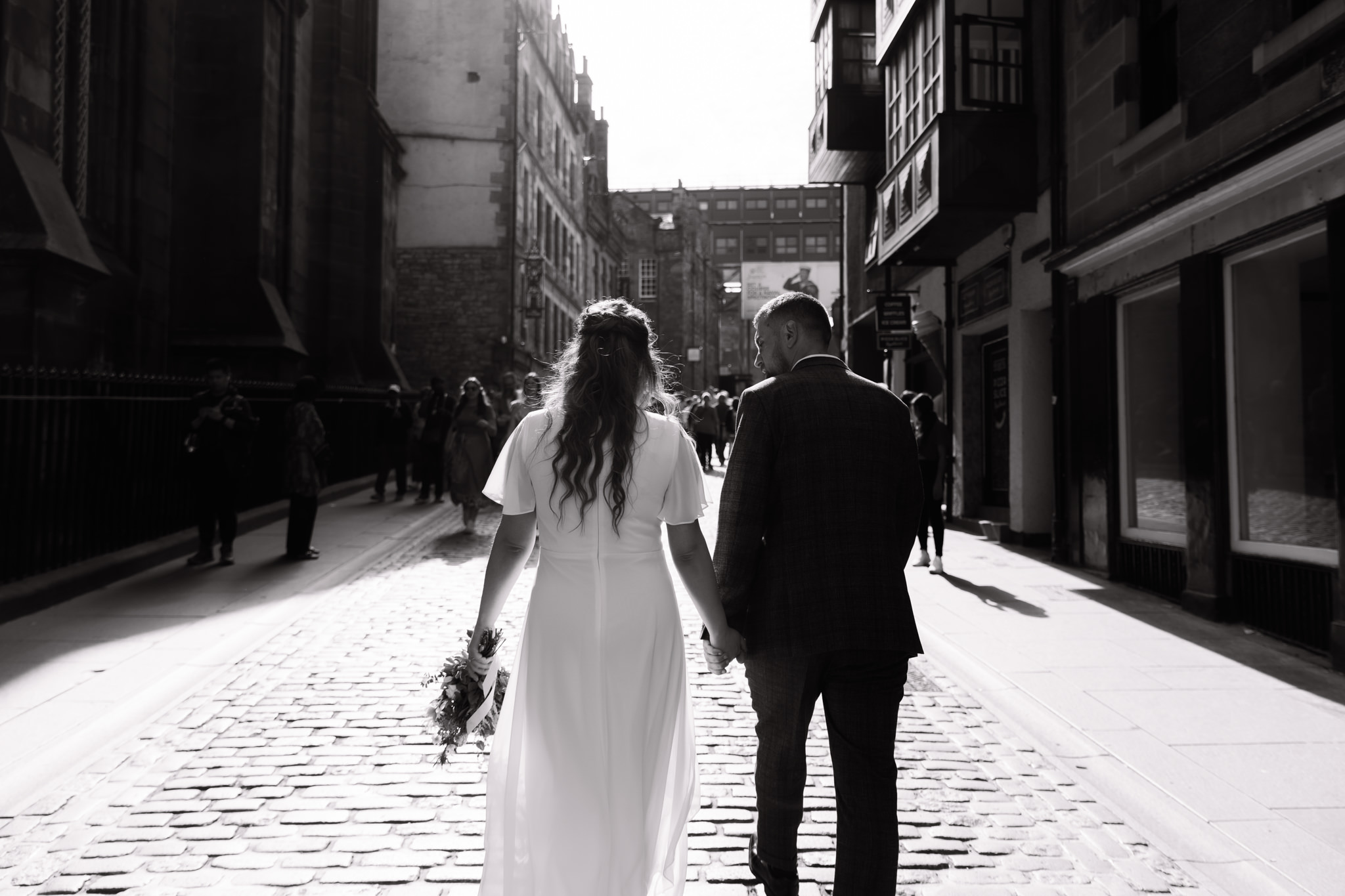 bride and groom walking up a cobbled road towards Canonball Restaurant