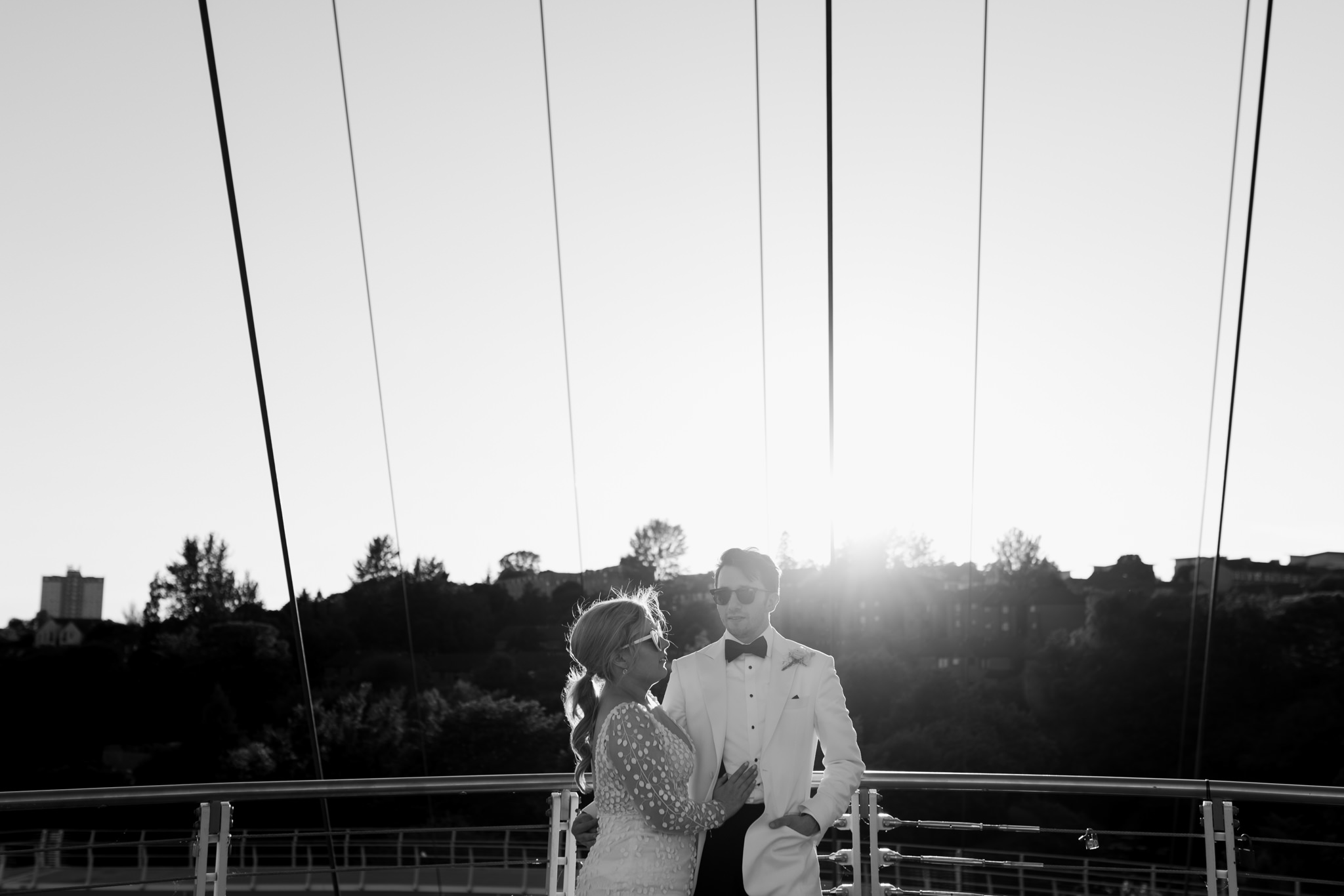 bride and groom standing in the sunshine wearing sunglasses 