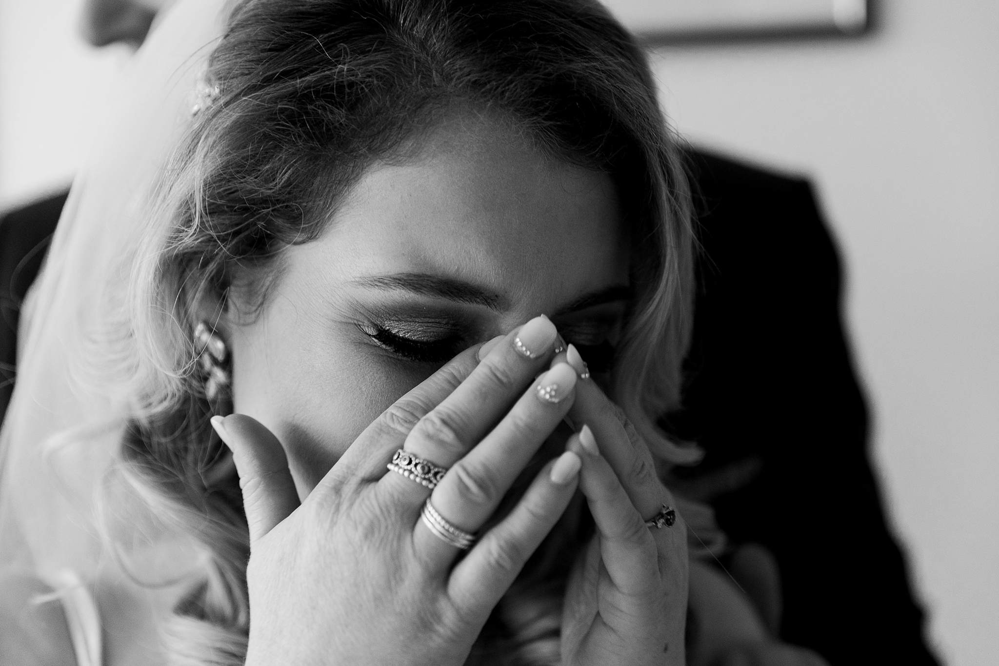 bride clutching hands to her face as she starts to cry