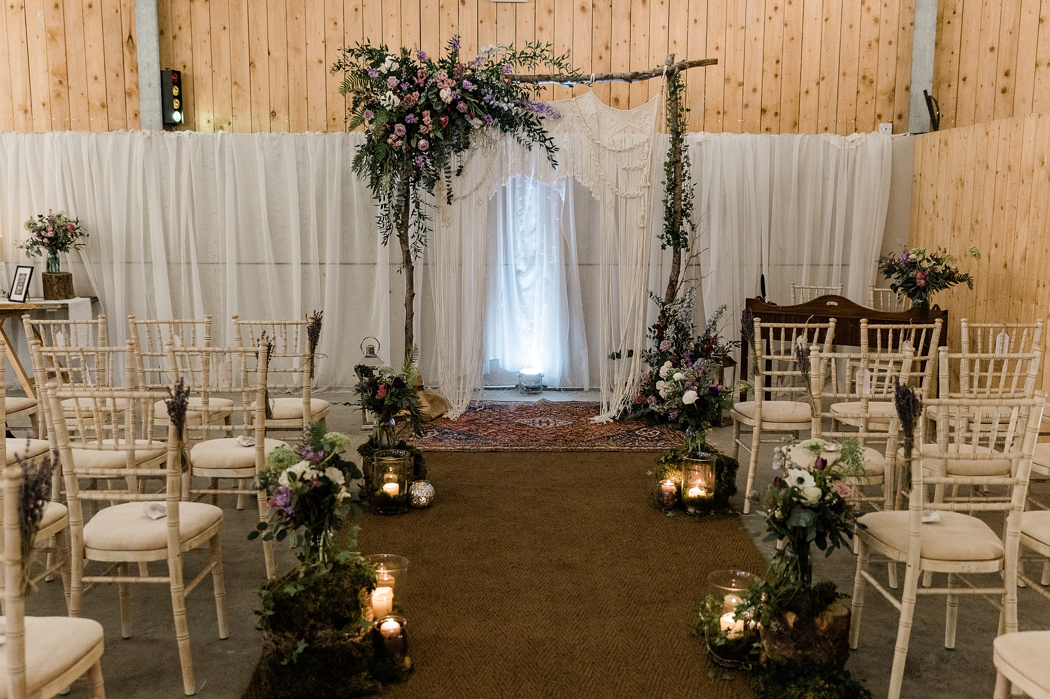wedding aisle and archway with flowers and candles at a wedding in the barn at Carrick Castle Estate