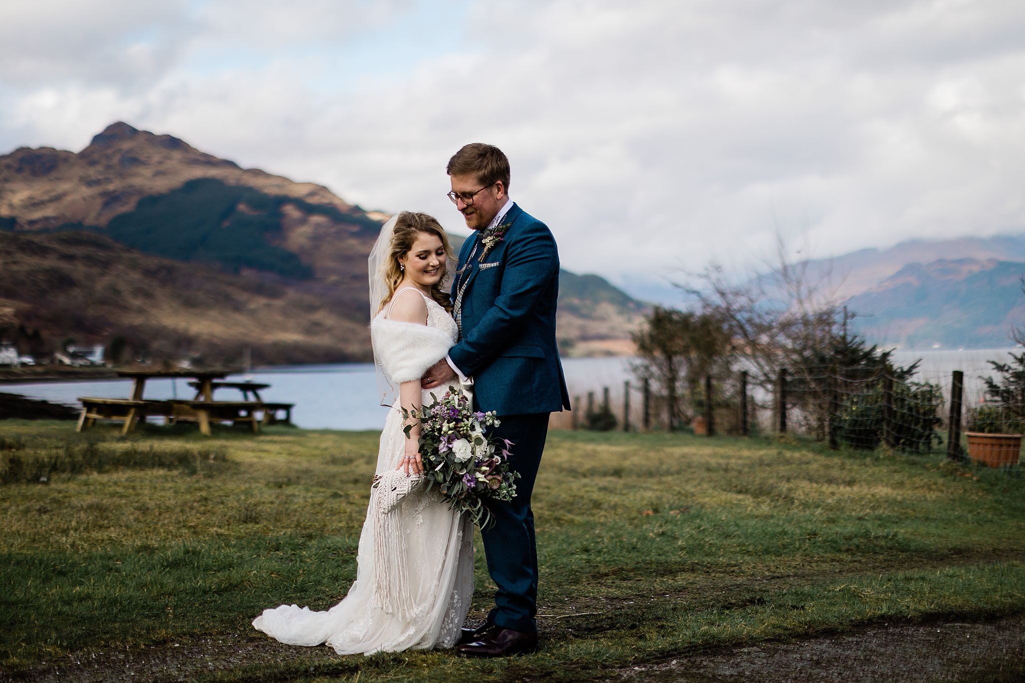 bride and groom smiling and embracing with Scottish hills in background