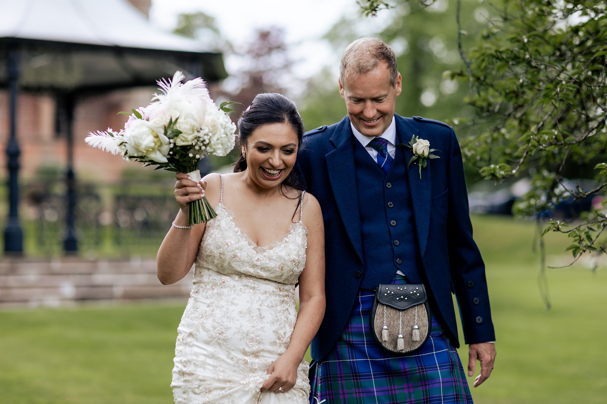 bride and groom smiling and walking, bride holding up dress and bouquet