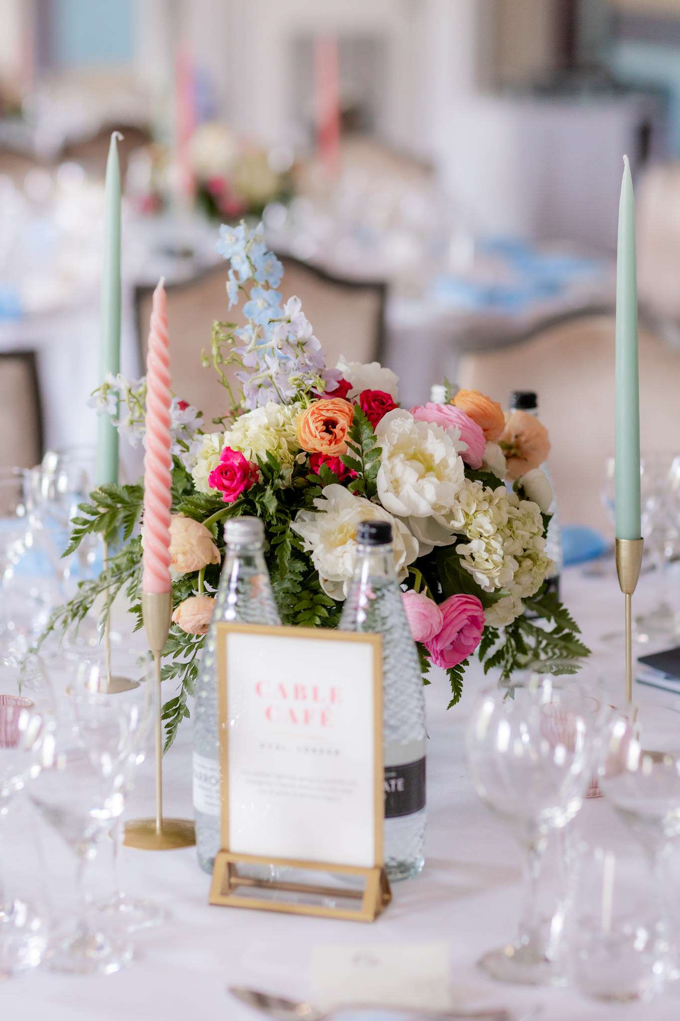 pink and white flowers and pink and green candles at a wedding table set 