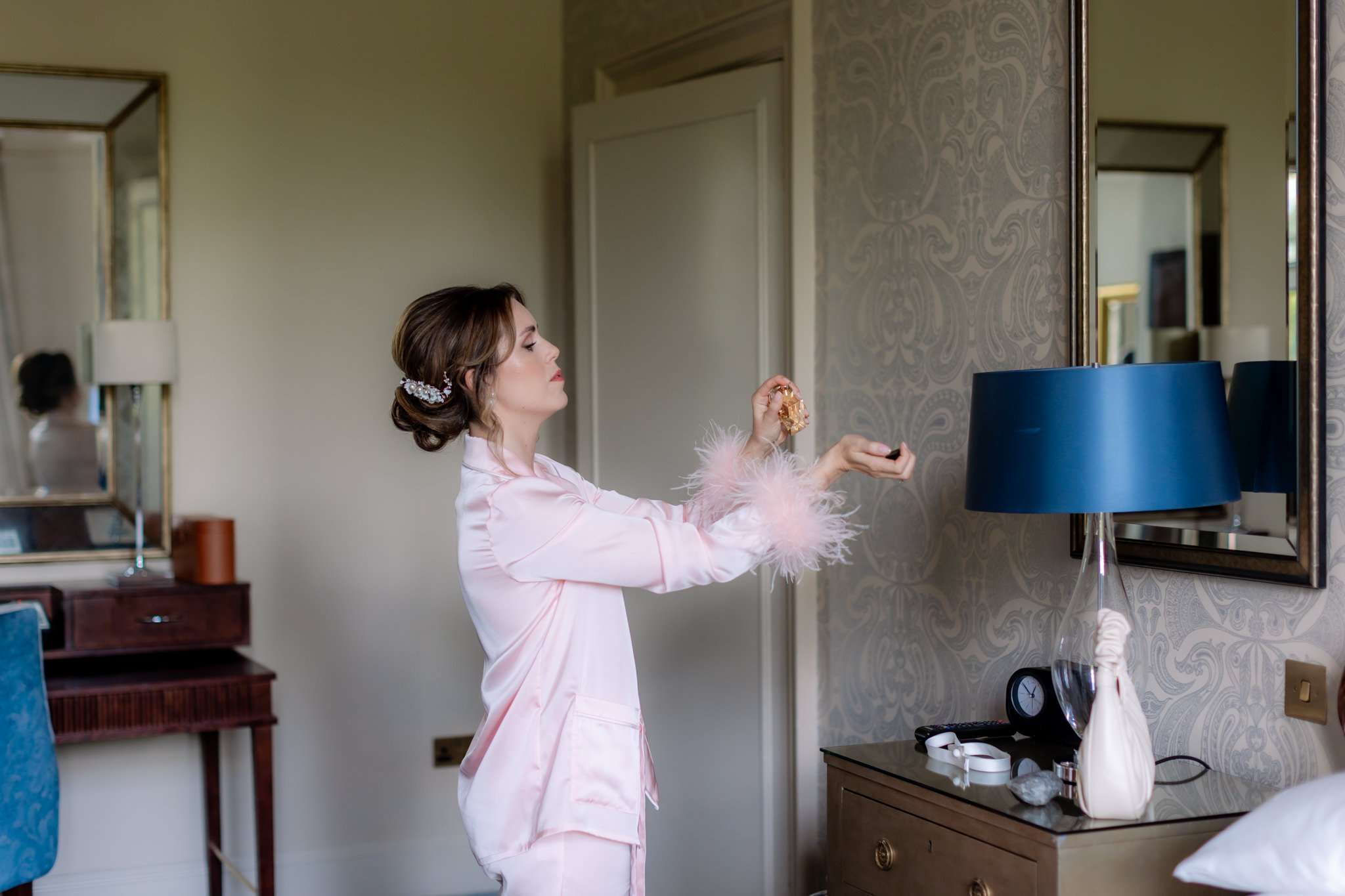 bride in pink silk pyjamas spraying her wrists with perfume, in Sir Walter Scott Suite at Caledonian Waldorf Astoria hotel 