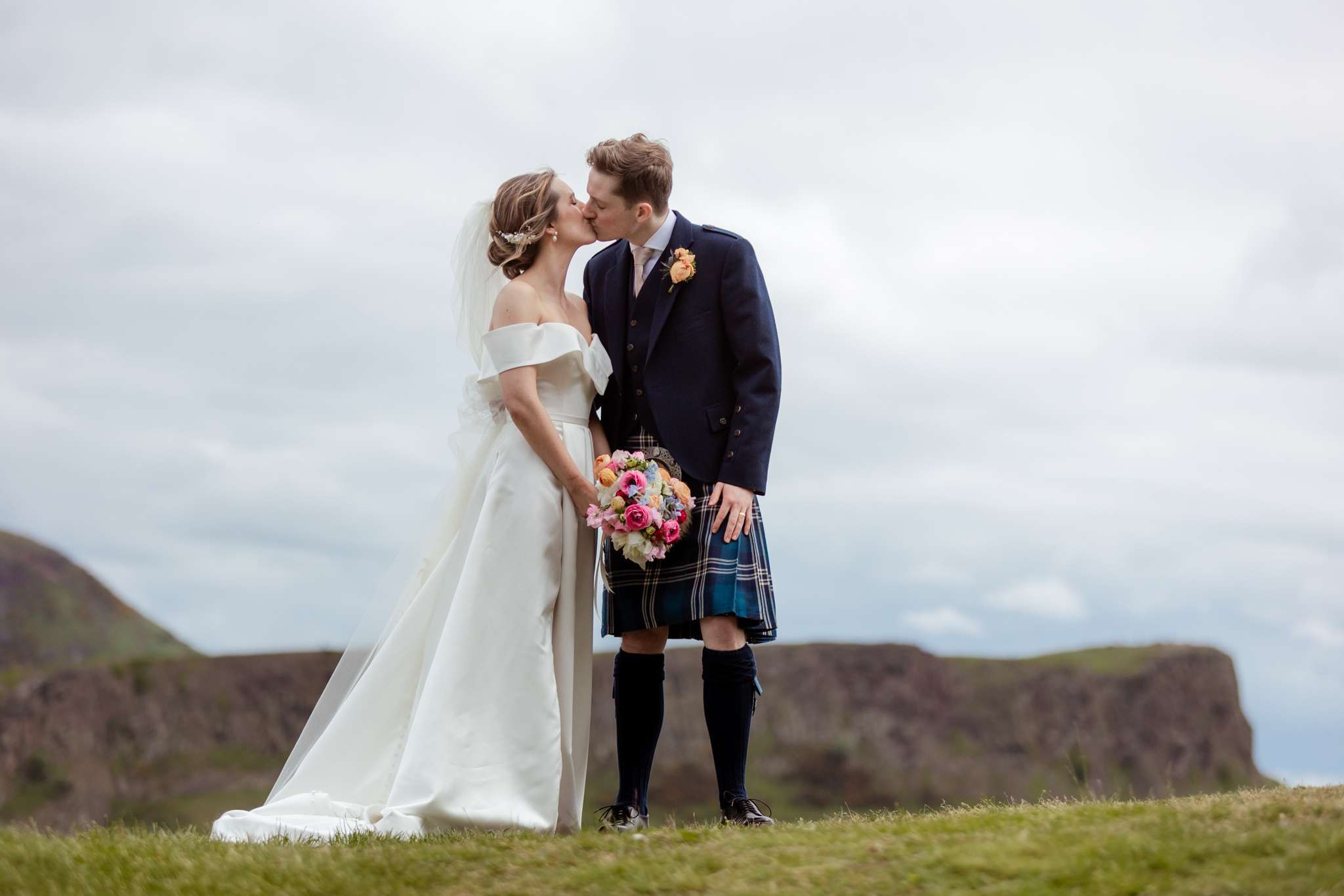 bride and groom kissing in front of Arthurs Seat, from  Carlton Hill, Edinburgh 