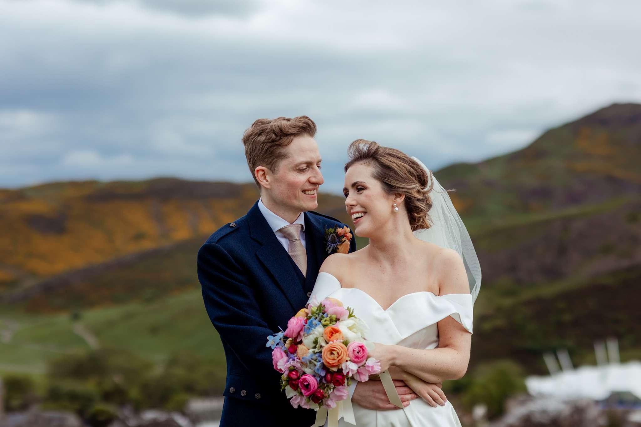 bride and groom embracing in front of Arthurs Seat, Edinburgh