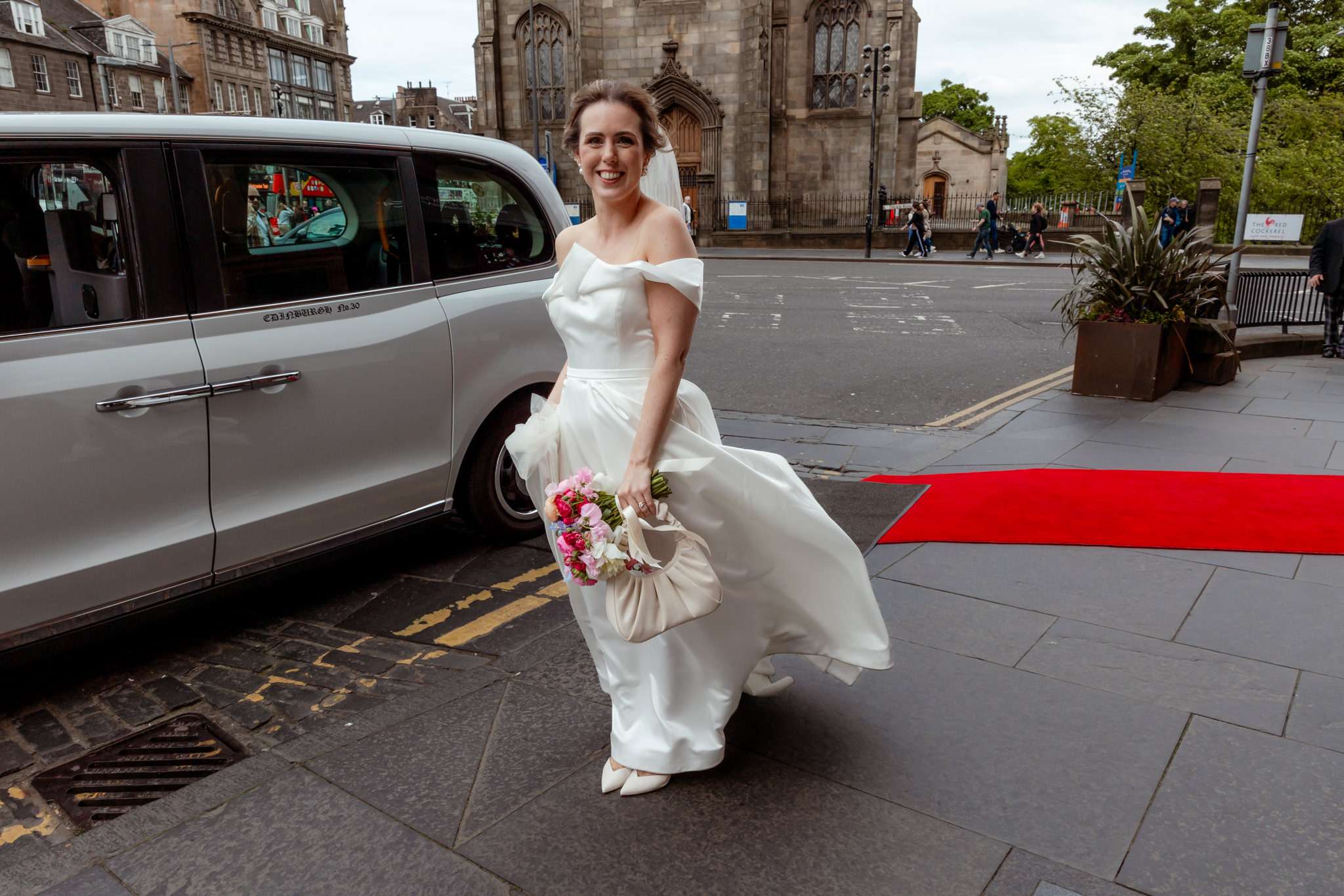bride standing outside Caledonian Waldorf Astoria Hotel in Edinburgh with a red carpet 