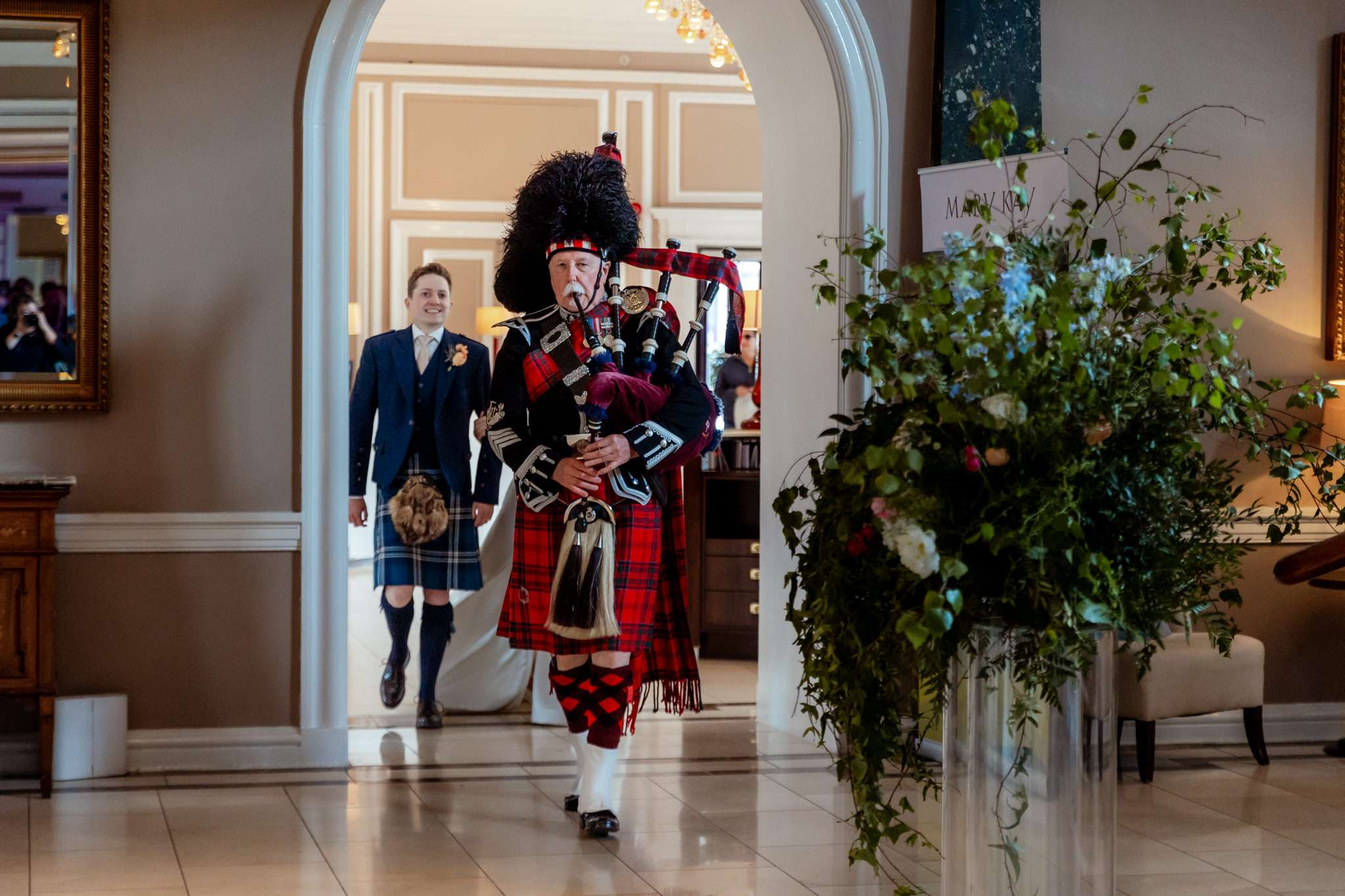 Highland wedding piper piping a bride and groom into their wedding at Caledonian Waldorf Hotel in Edinburgh 