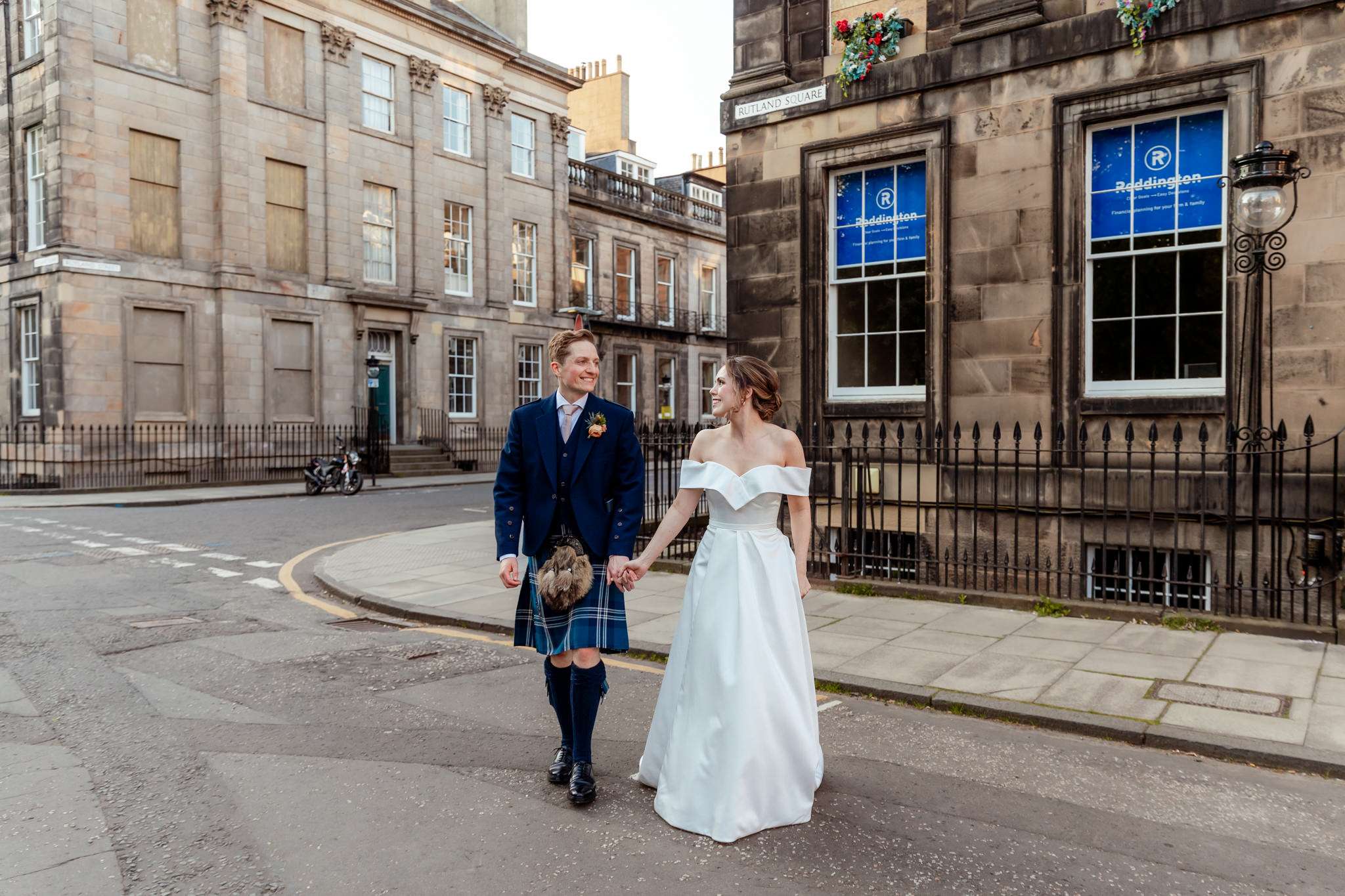 Bride and groom wandering around New town in Edinburgh smiling at each other