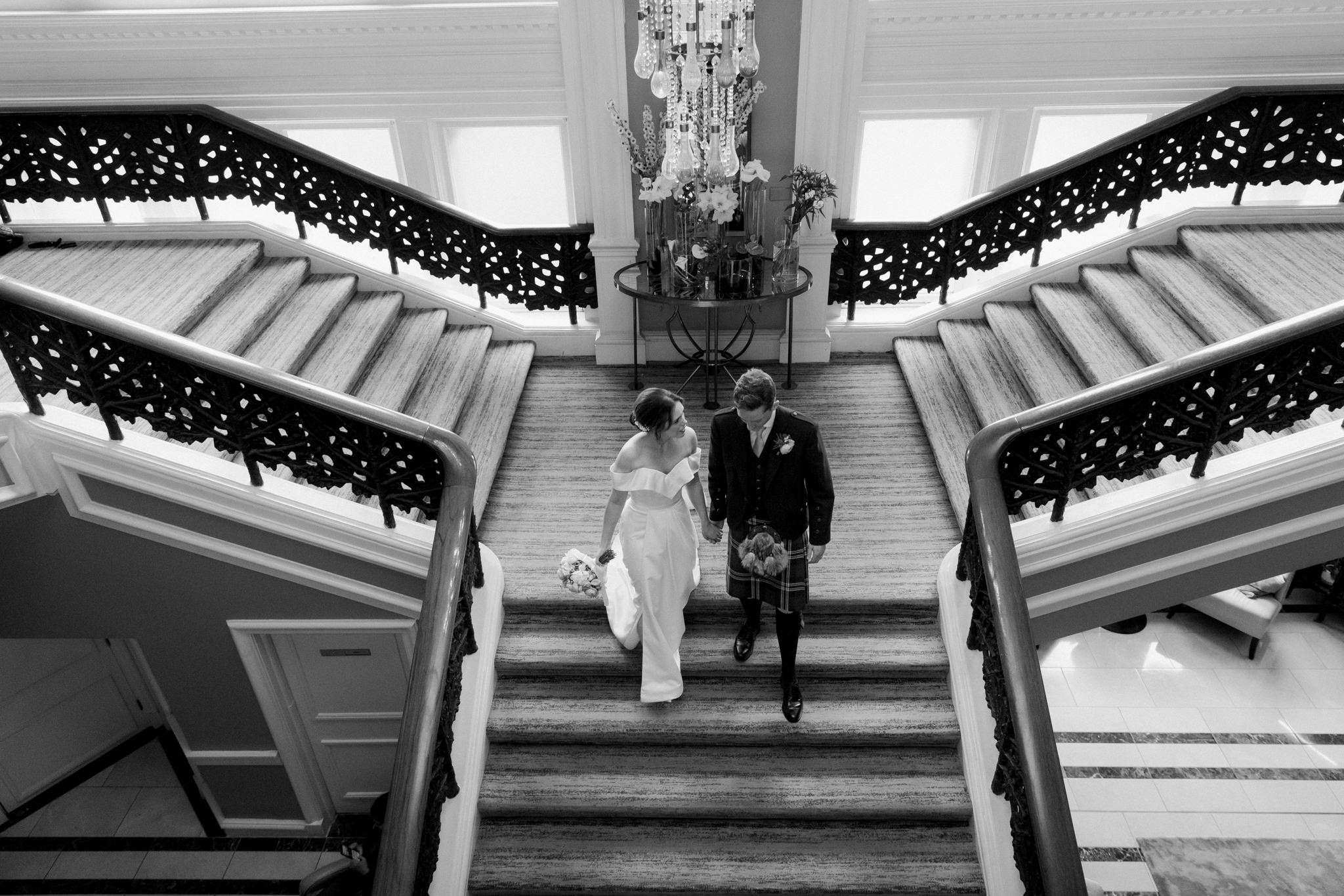 bride and groom walking down a staircase at a wedding at Caledonian Waldorf Hotel in Edinburgh 