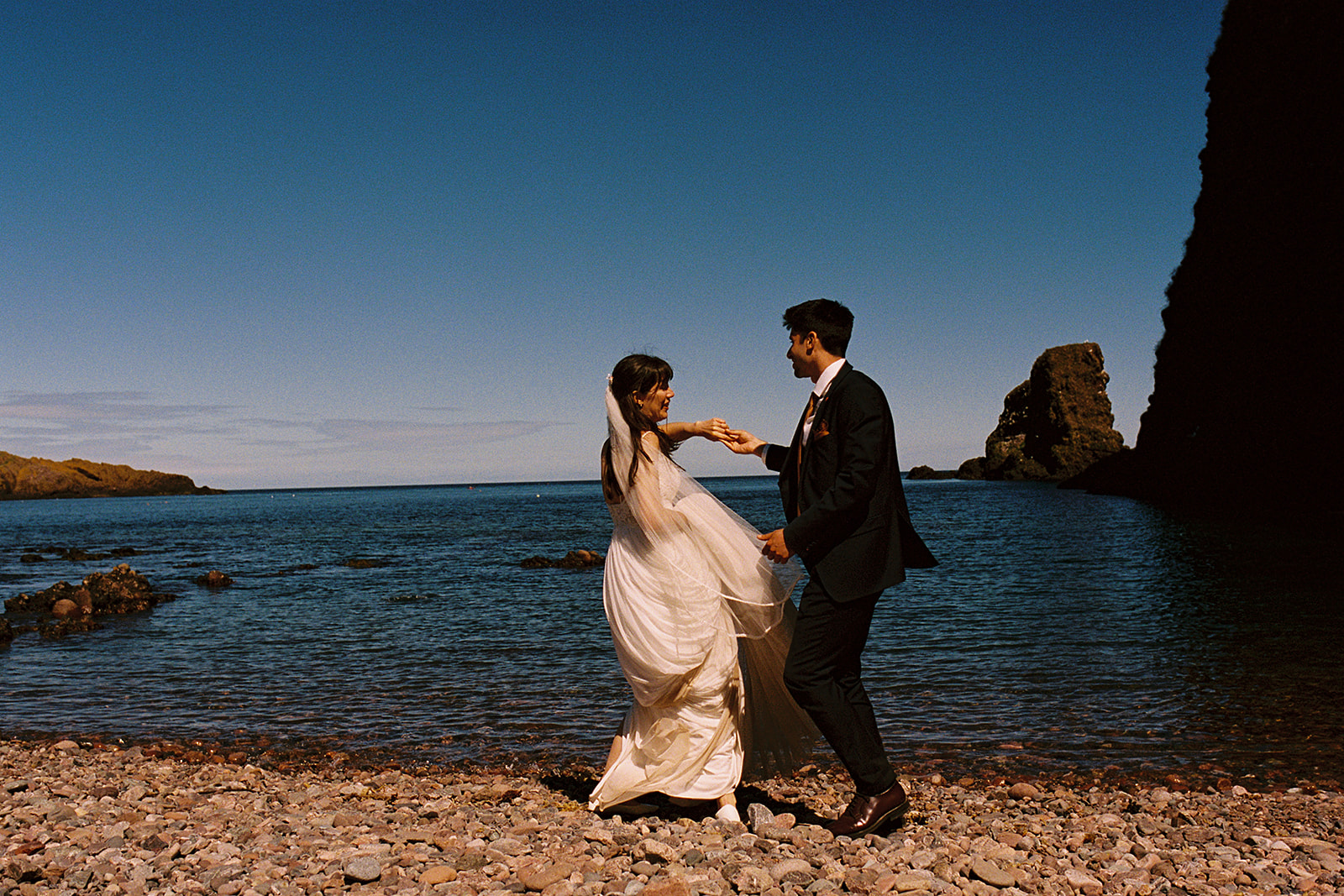 analogue film photography of bride and groom dancing on a beach in Stonehaven