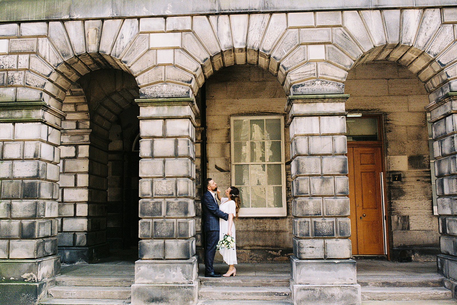 bride and groom standing under Victorian building arches, in Edinburgh