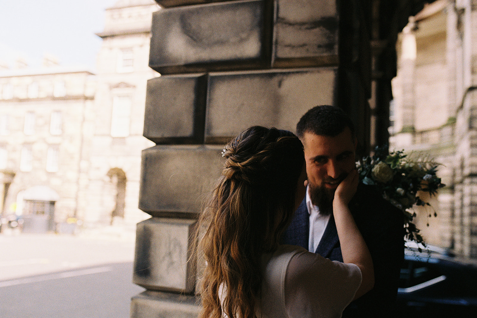 analogue film photography of a bride stroking a groom's face at a wedding in Edinburgh, Scotland