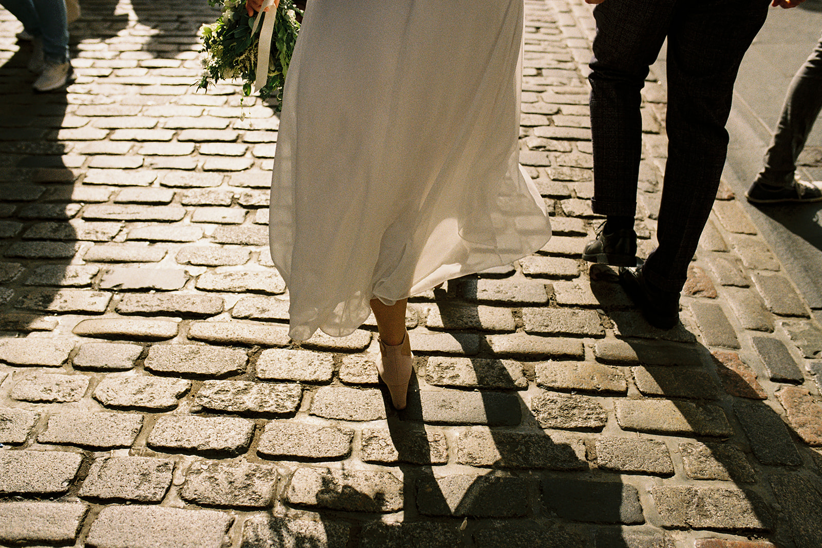 analogue film photography of a bride and groom walking along a cobbled road in Edinburgh