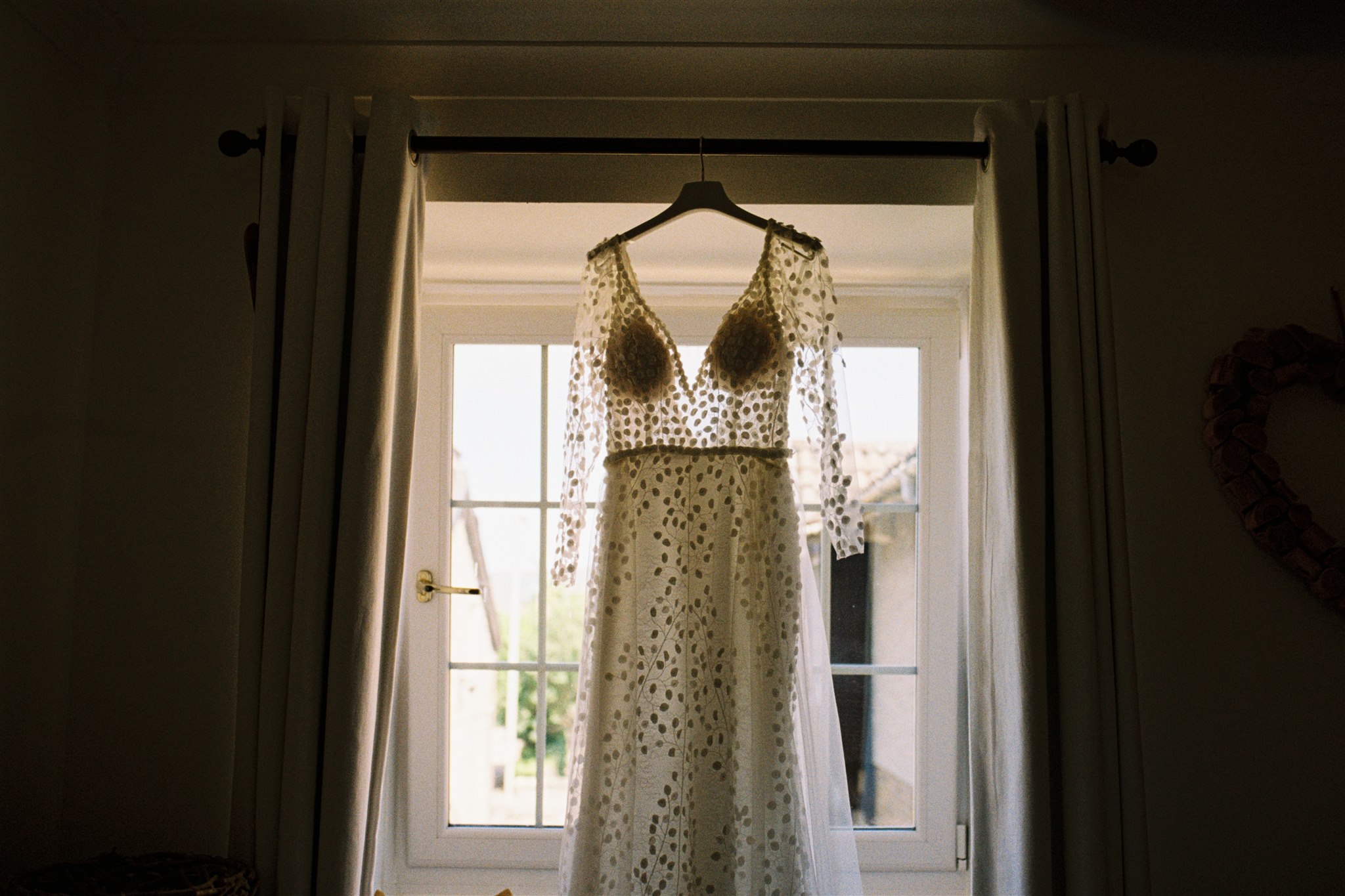 a white wedding dress hanging in a window 