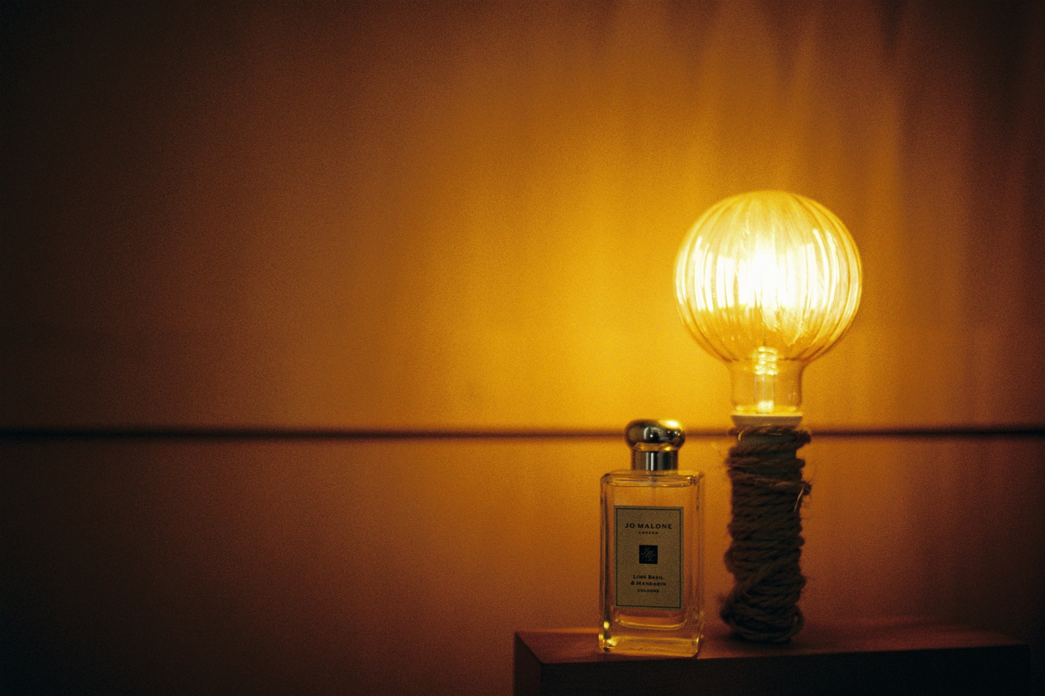 analogue film photograph of a perfume bottle next to a tungsten light 