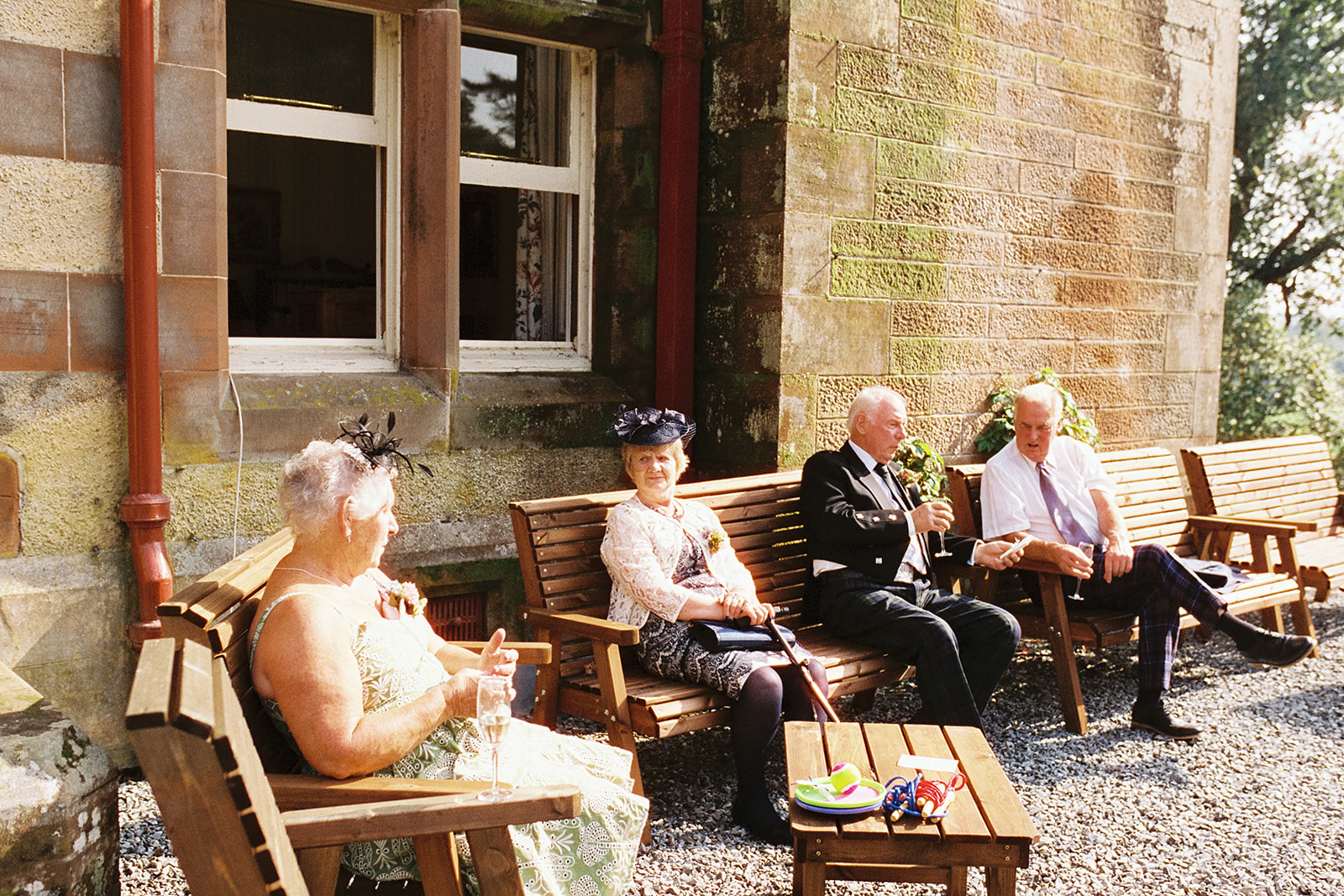 wedding guests sitting in the sunshine outside Dungarthill House, Dunkeld