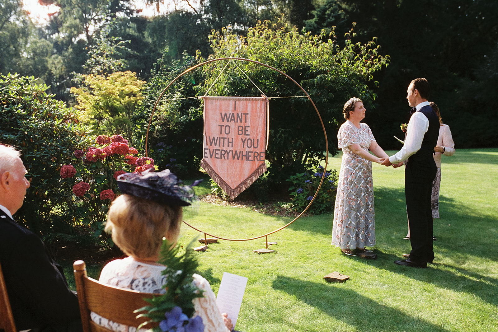 analogue film photograph of an outdoor wedding ceremony with a velvet banner 