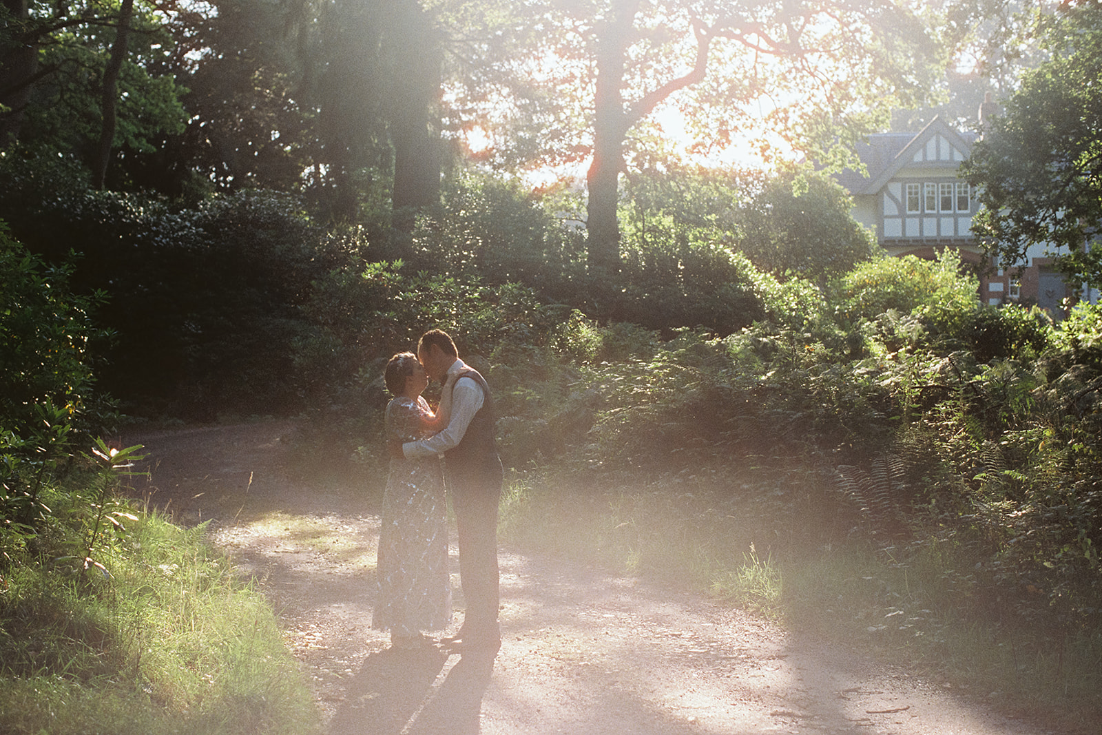 hazy analogue film photograph of a bride and groom kissing on a country path in Dunkeld, Perthshire