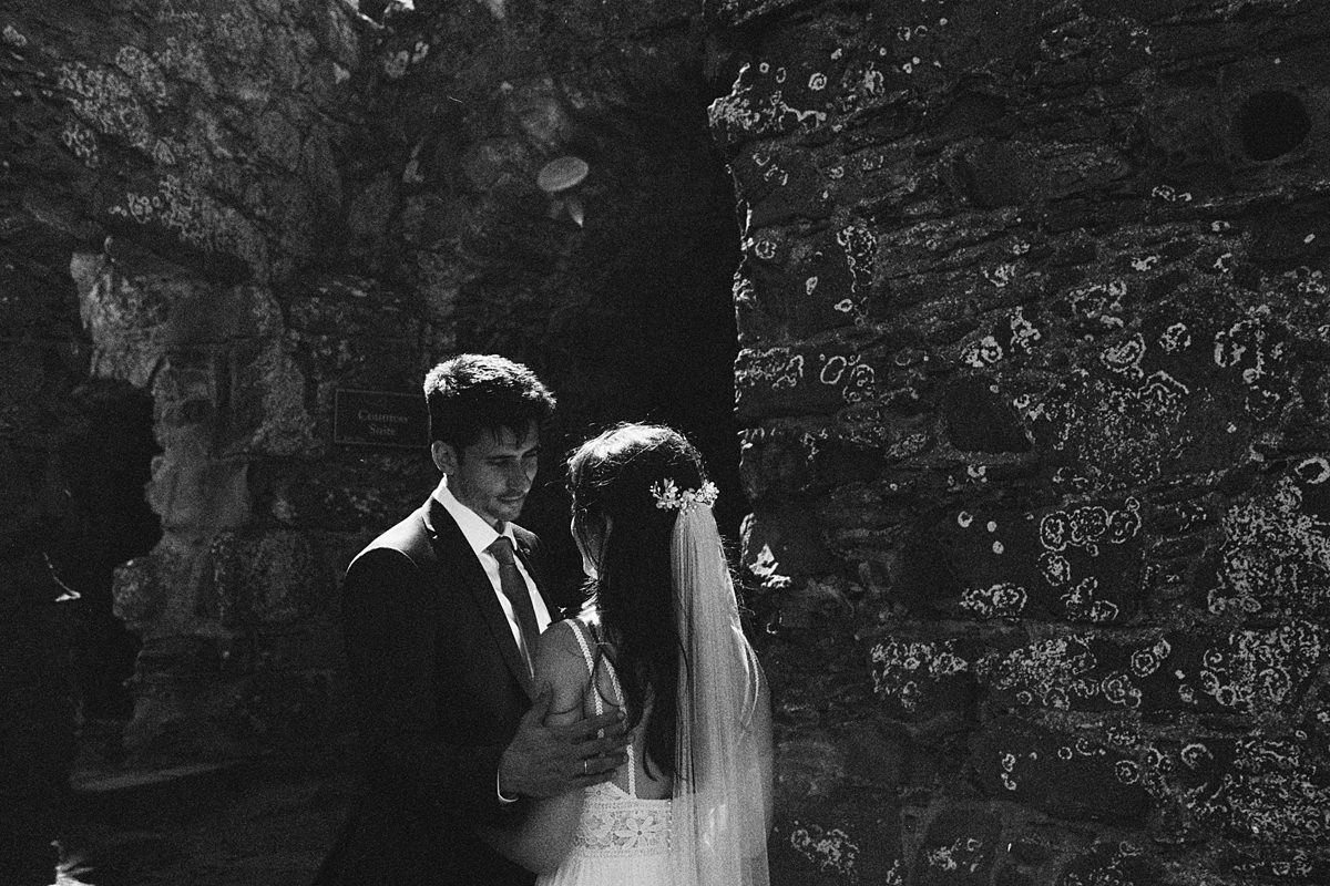 black and white 35mm film photo of a bride and groom in the ruins of Dunnottar Castle, Stonehaven, Scotland