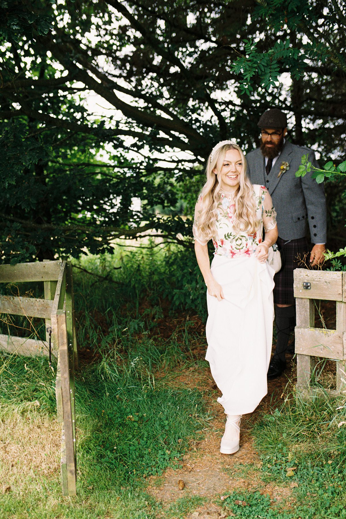 35mm analogue film photograph of bride and groom walking through a gate out of a woodland