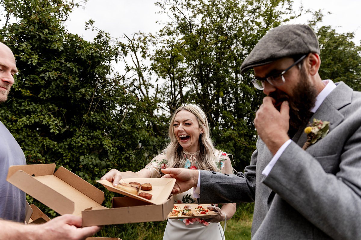 bride and groom enjoying canapes from a food take away box