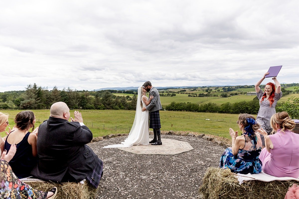 bride and groom first kiss during their outdoor wedding ceremony at family farm in Scotland