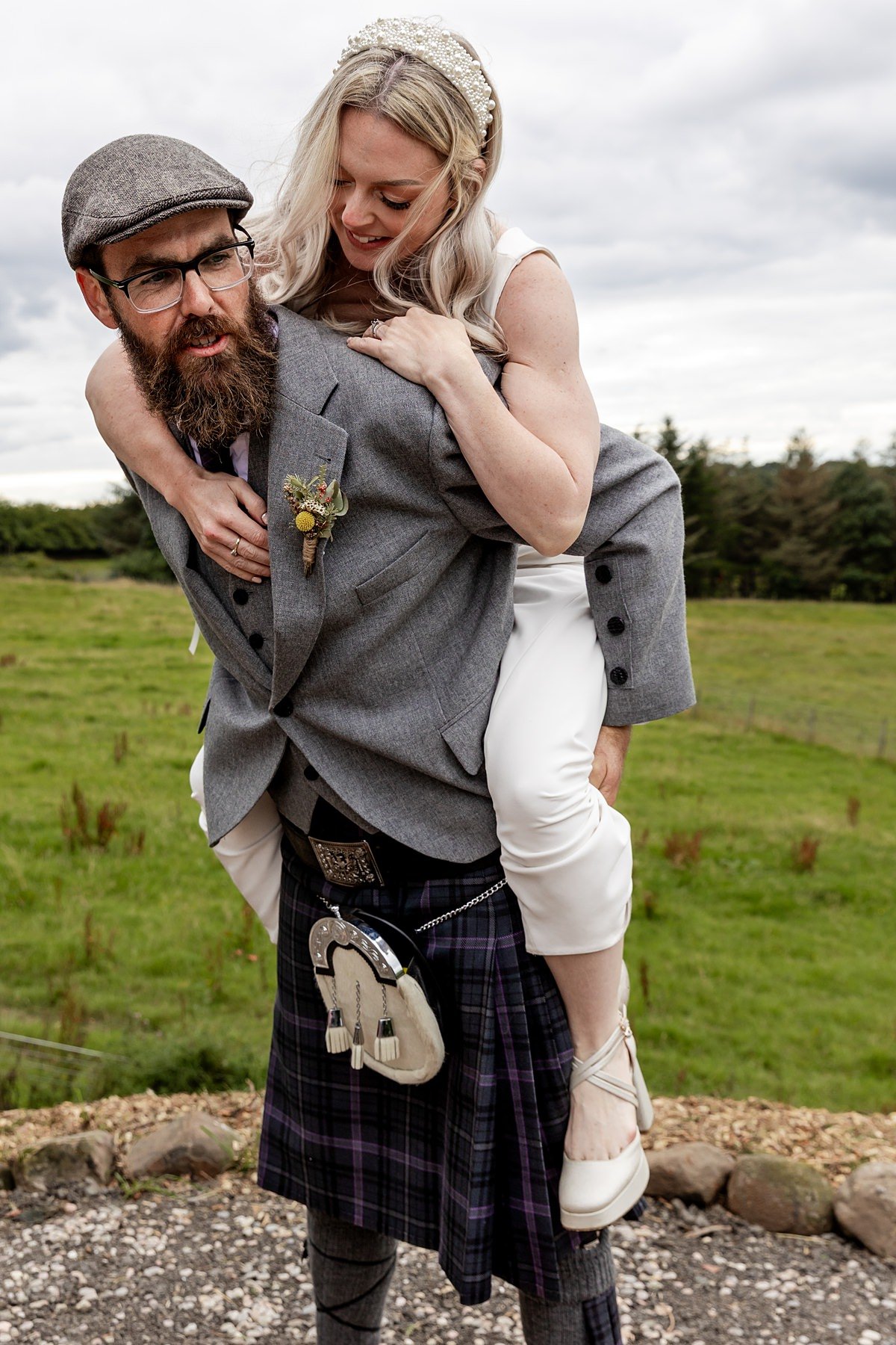 bride on the back of a groom in a kilt