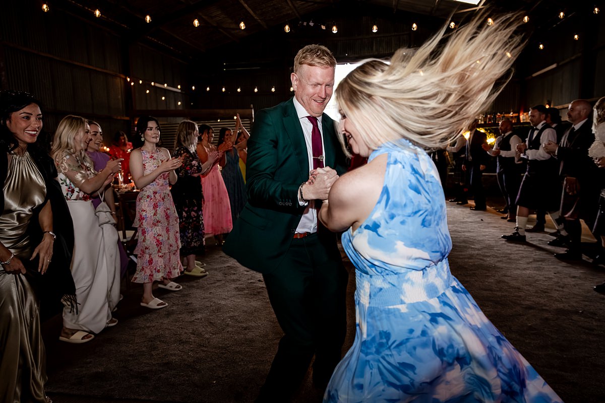 wedding guests ceilidh dancing at a family farm wedding in Scotland