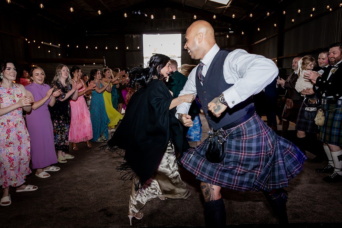 wedding guests ceilidh dancing at a family farm wedding in Scotland