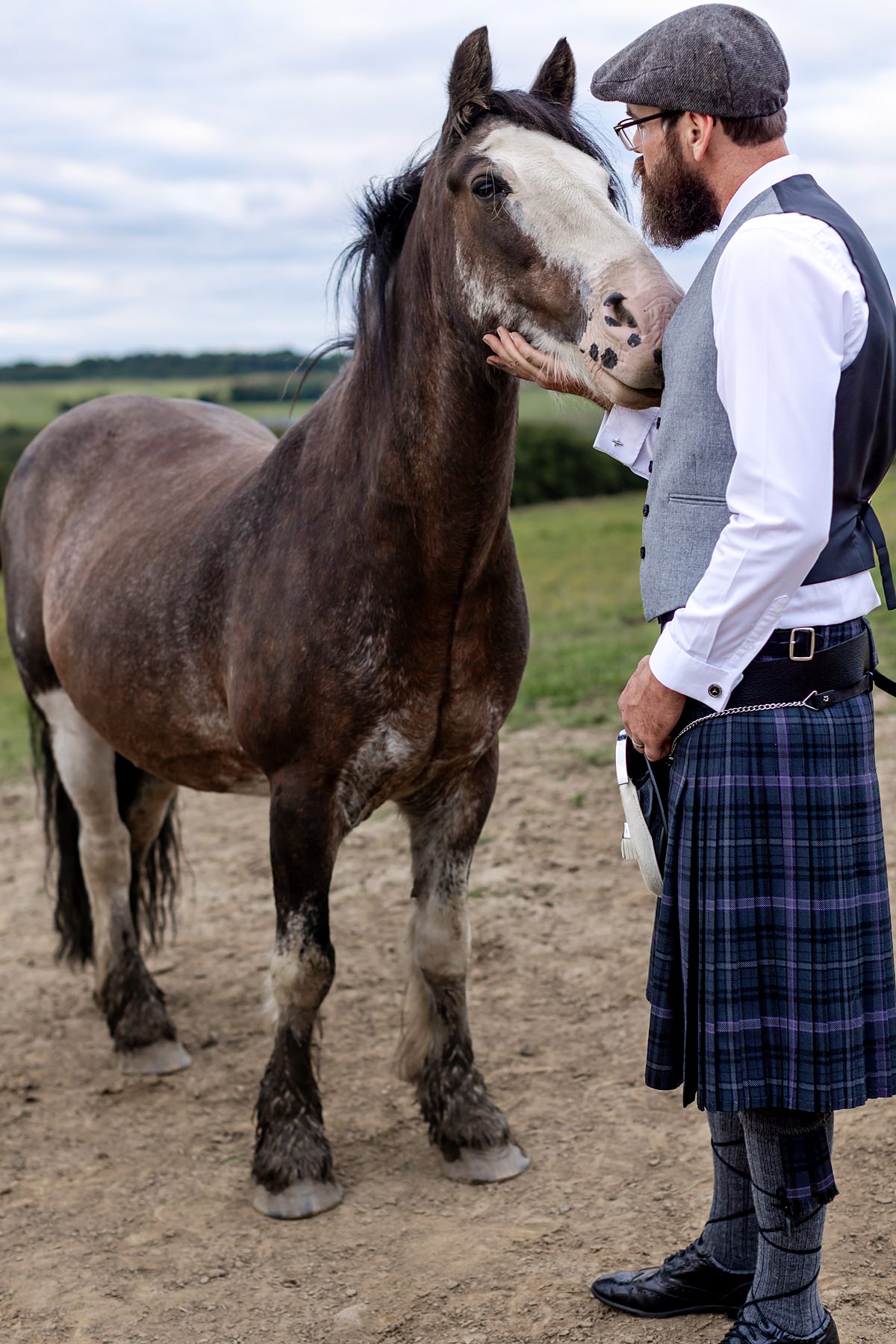 groom scratching the chin of a brown and white horse