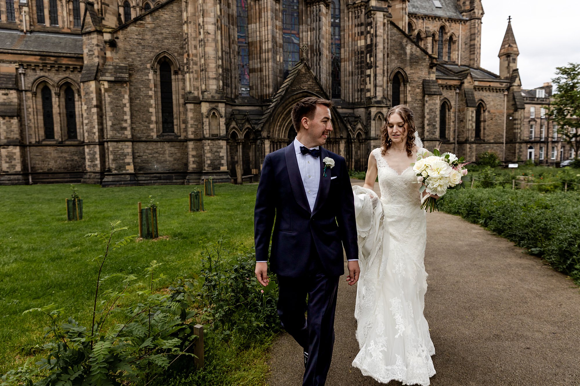bride and groom walking along a path outside St Mary's Episcopal Church in Edinburgh