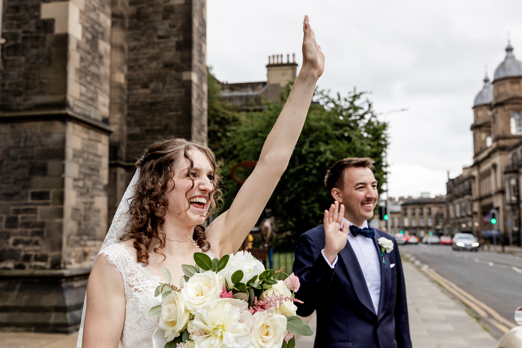 bride and groom waving outside St Mary's Episcopal Church in Edinburgh