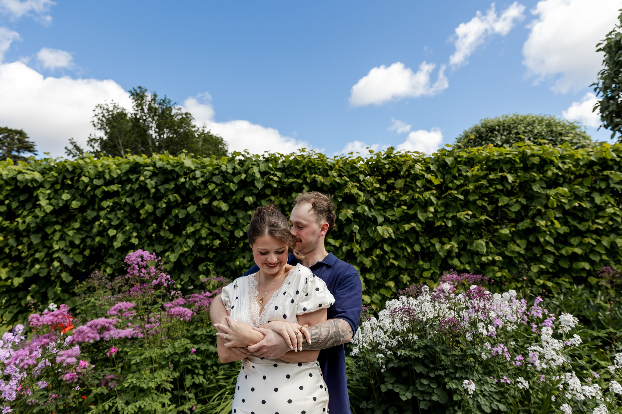 man cuddling his fiancee from behind in a garden at Dunrobin castle